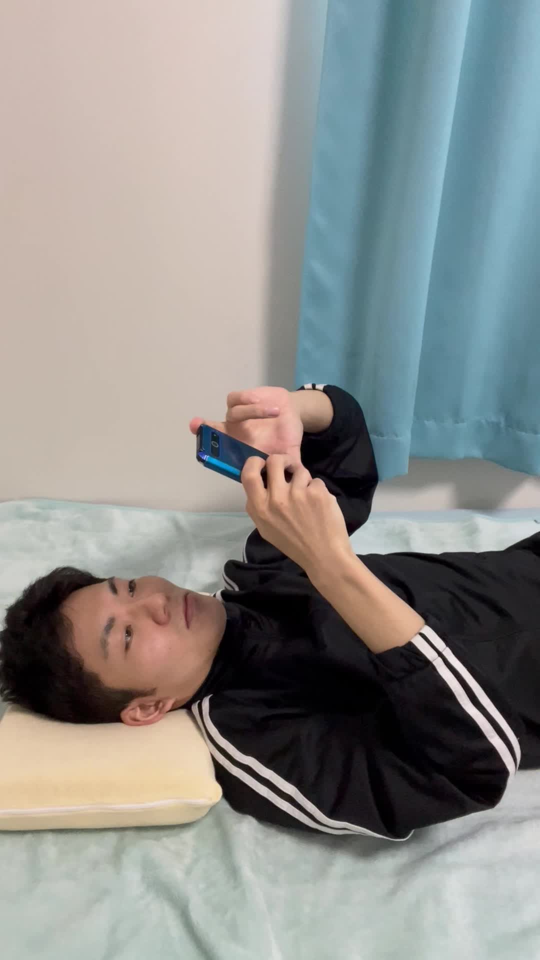 ベッドで横になり、スマホを見ながら「次に何を送ろう？」と考え込む動作