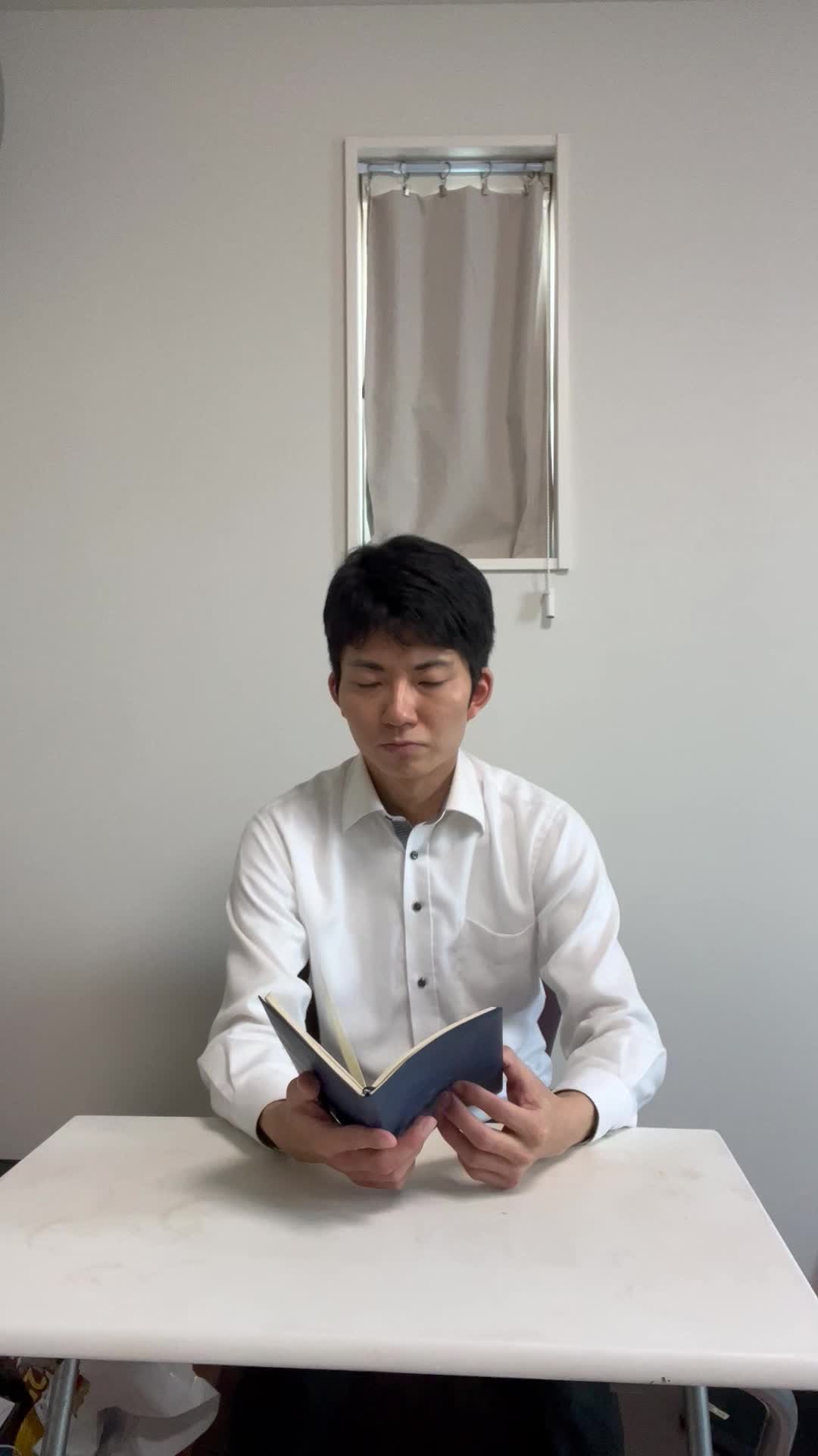 椅子から立ち上がり、手帳を閉じて「次のステップに進む準備完了」風のポーズを取る姿