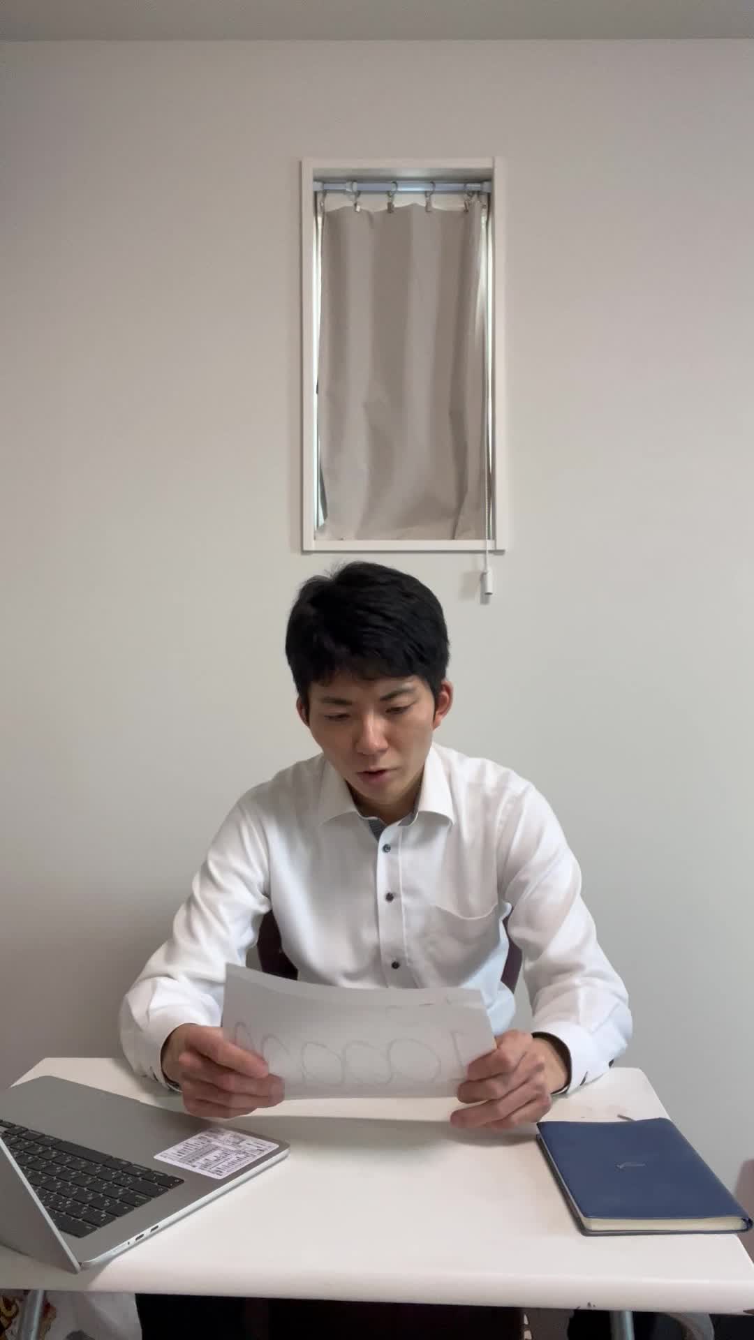 テーブルで紙を見つめ、「次の一手を決めた」風の自信を見せる表情