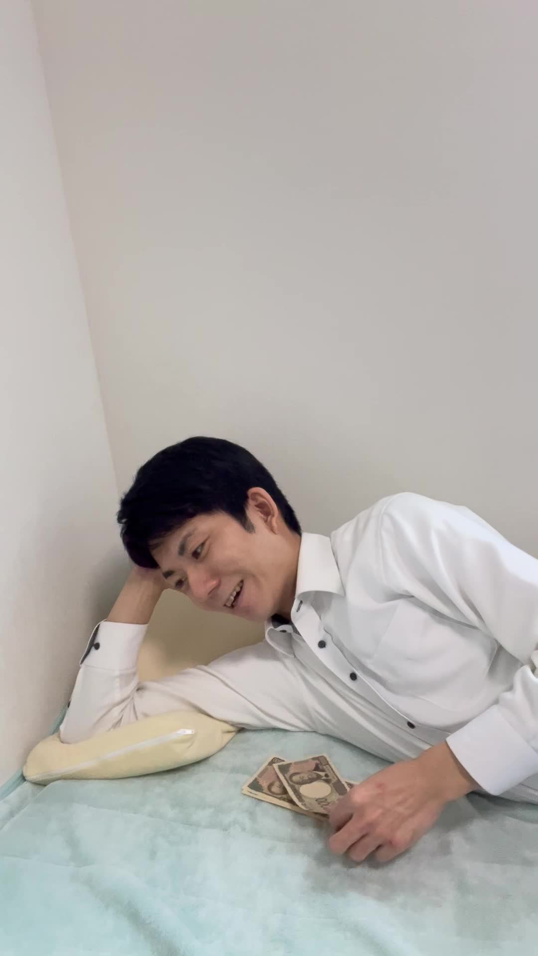 ベッドで寝転びながら、お札を1枚ずつ並べて「将来の資産」を思い描く姿