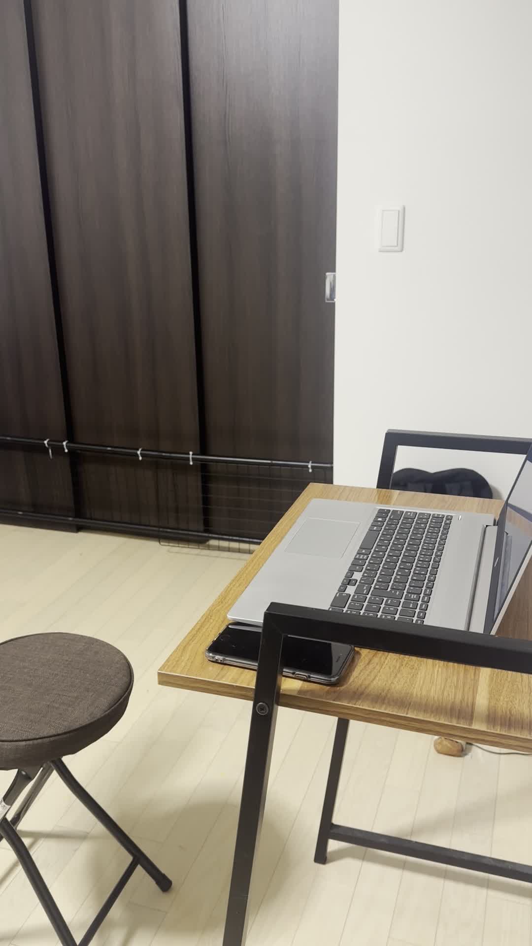 椅子に座り、仕事中にスマホを確認し、メッセージが来てにやけてしまう様子