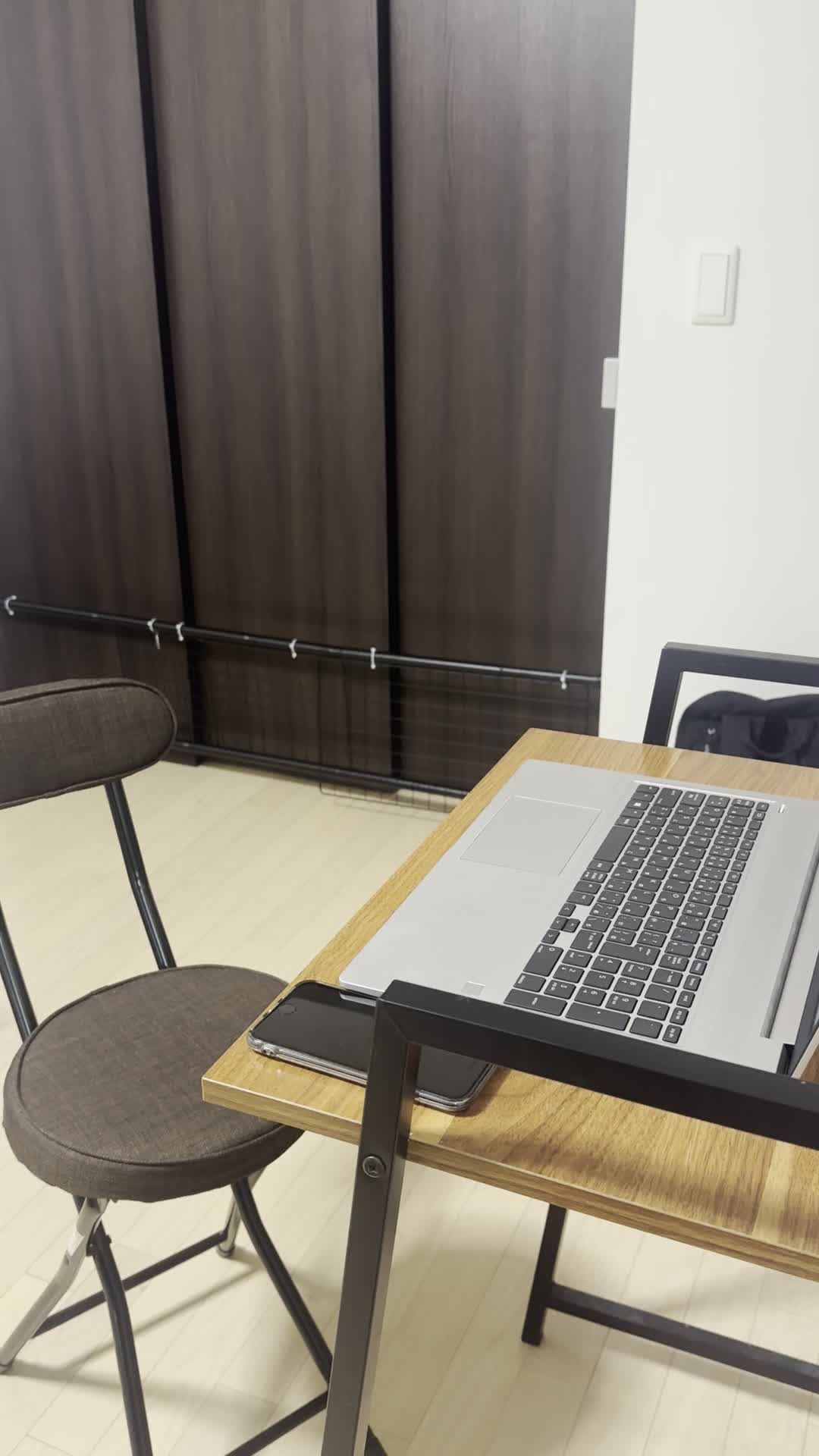 椅子に浅く腰掛け、スマホを握りしめながら「次のメッセージ、早く来ないかな」と待つ動作