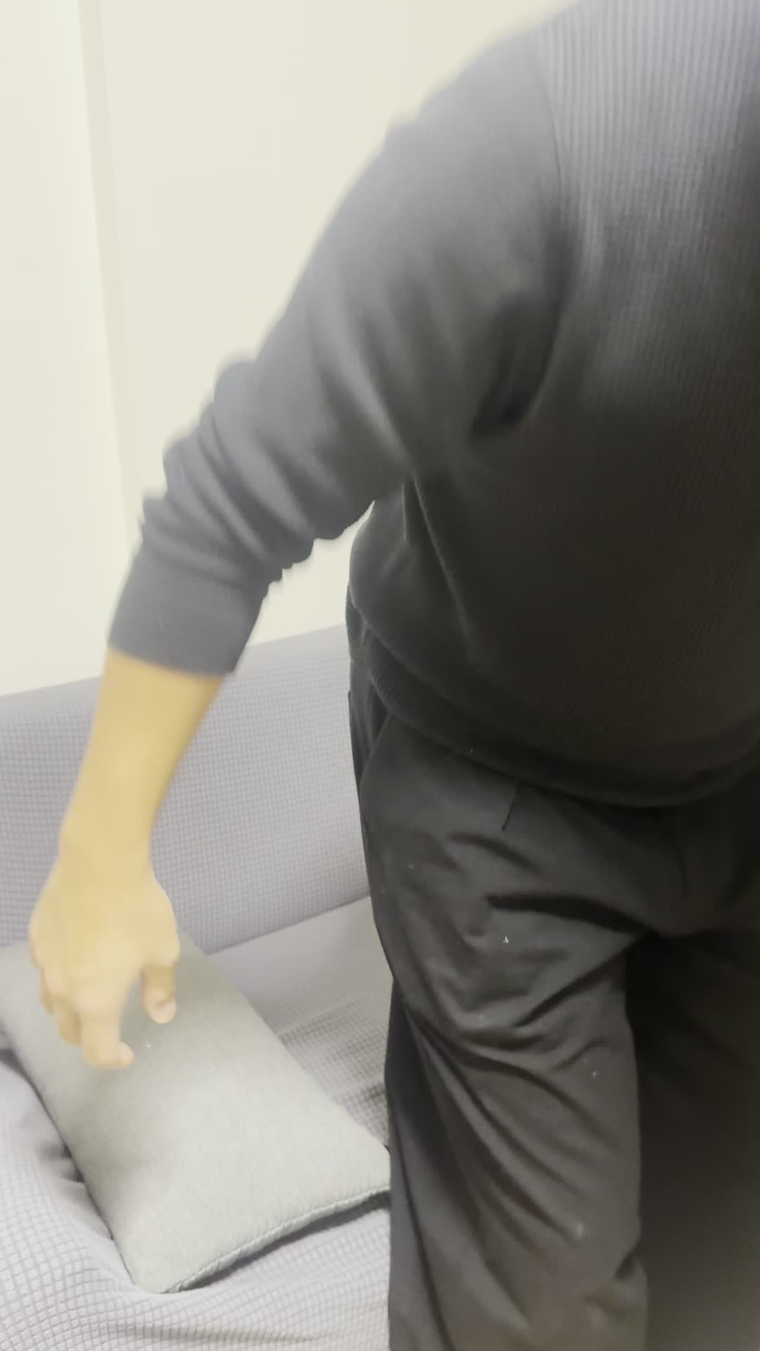 ソファでクッションを抱きしめながら、「今日も連絡ないのかな」と少し落ち込む表情