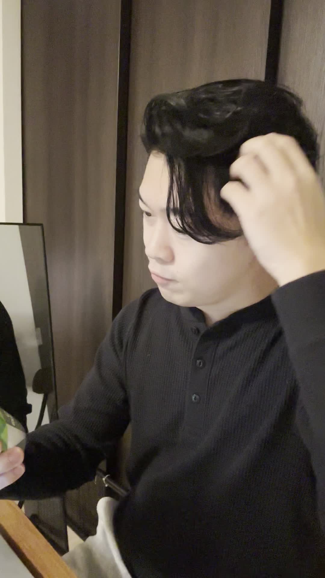 椅子に浅く腰掛け、髪を手ぐしで整えながら「このシャンプー試してみよう」と決意する表情