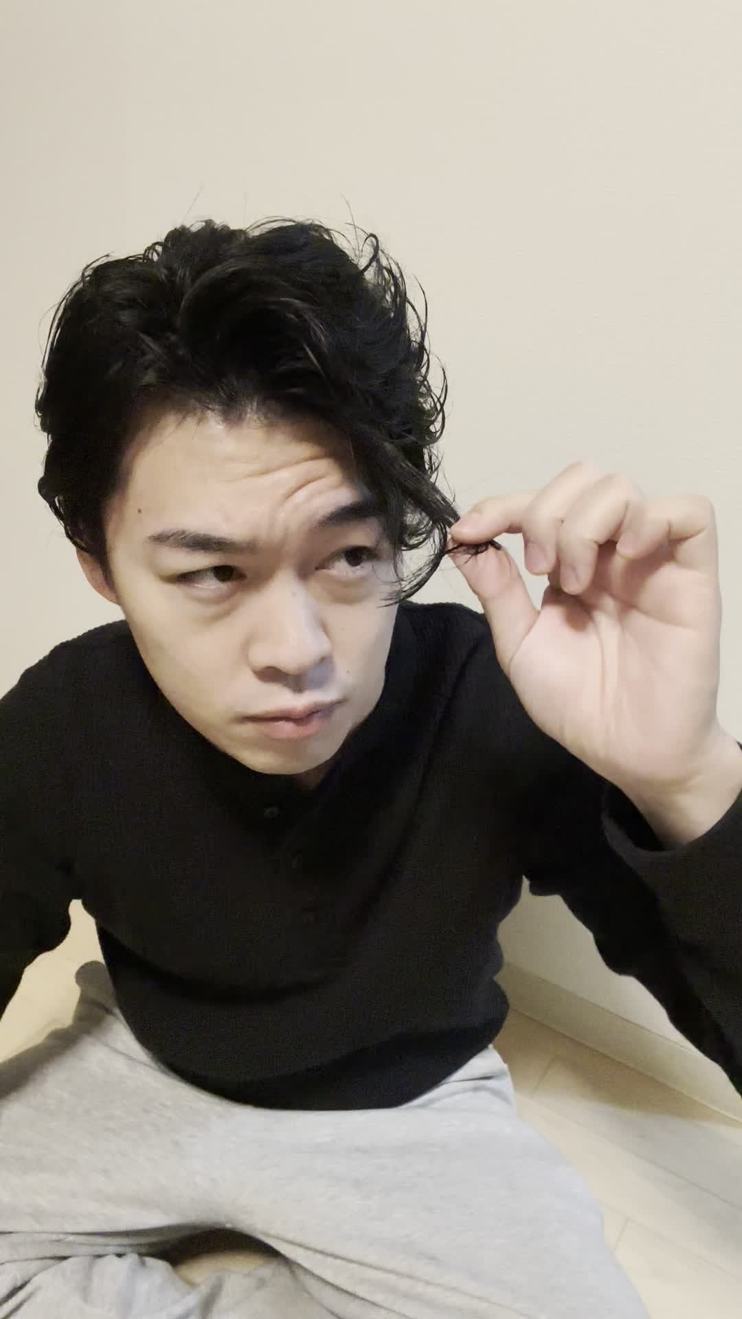 床で膝を立てて座り、「髪がまとまらなくて朝から大変」と困った様子を見せる仕草