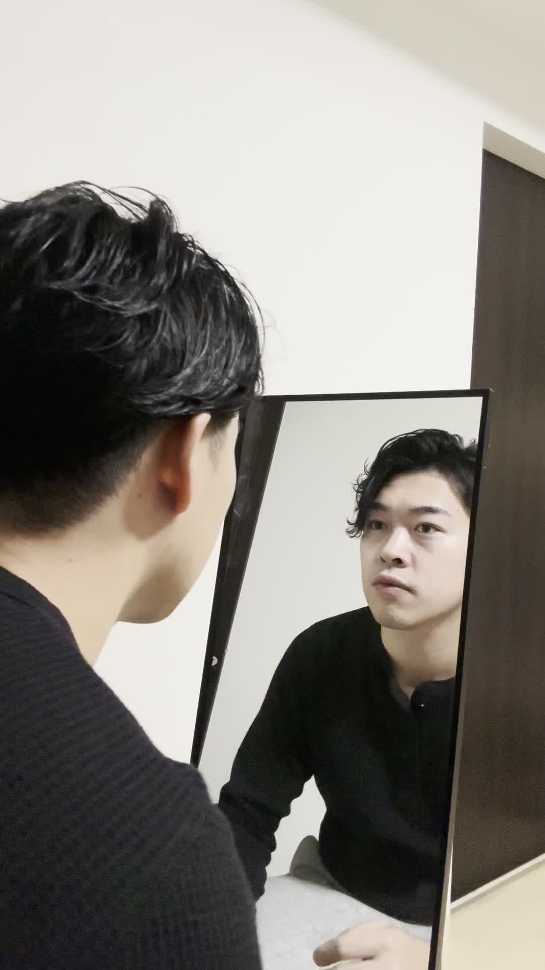 鏡の前で顔の左右を比べながら、「左右差が気になる」と指でなぞる動作