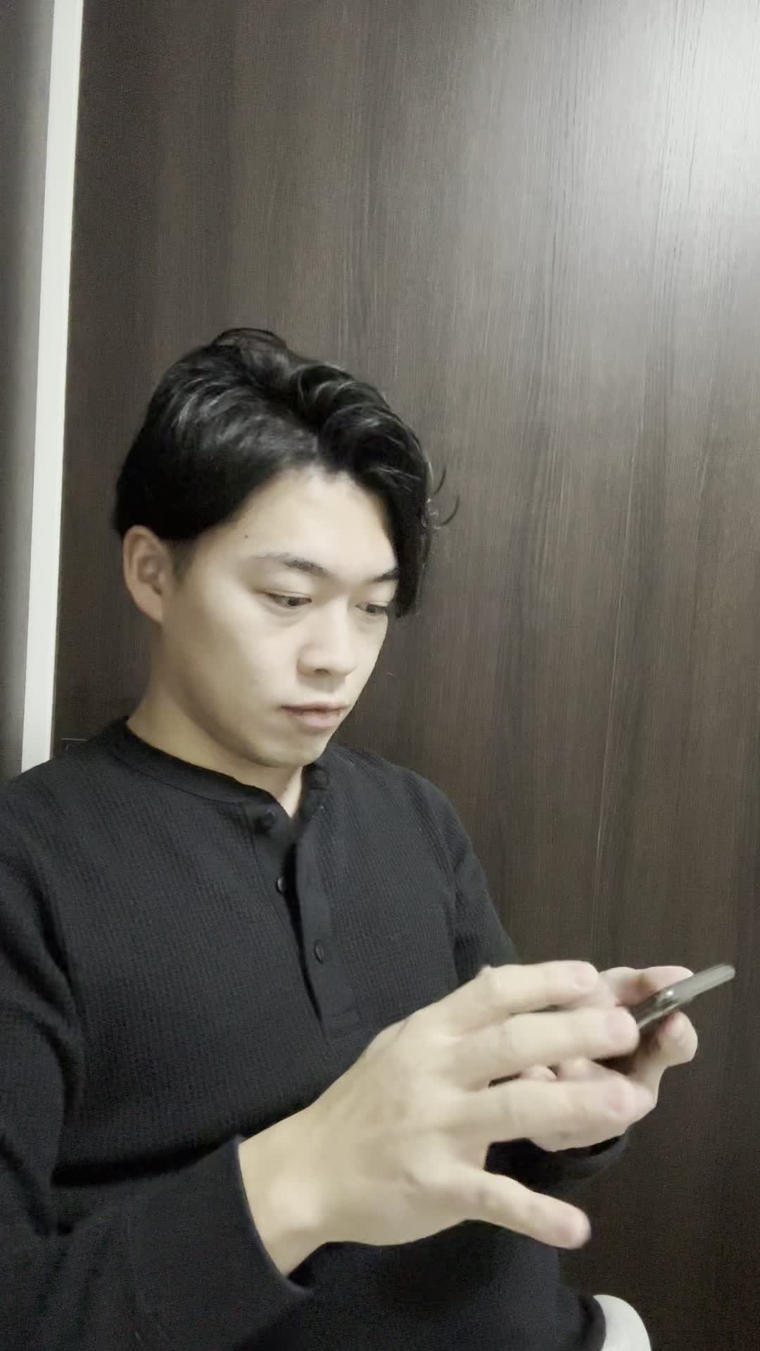 椅子に腰掛け、スマホで「ビフォーアフター写真」を見て驚きの表情を浮かべる姿