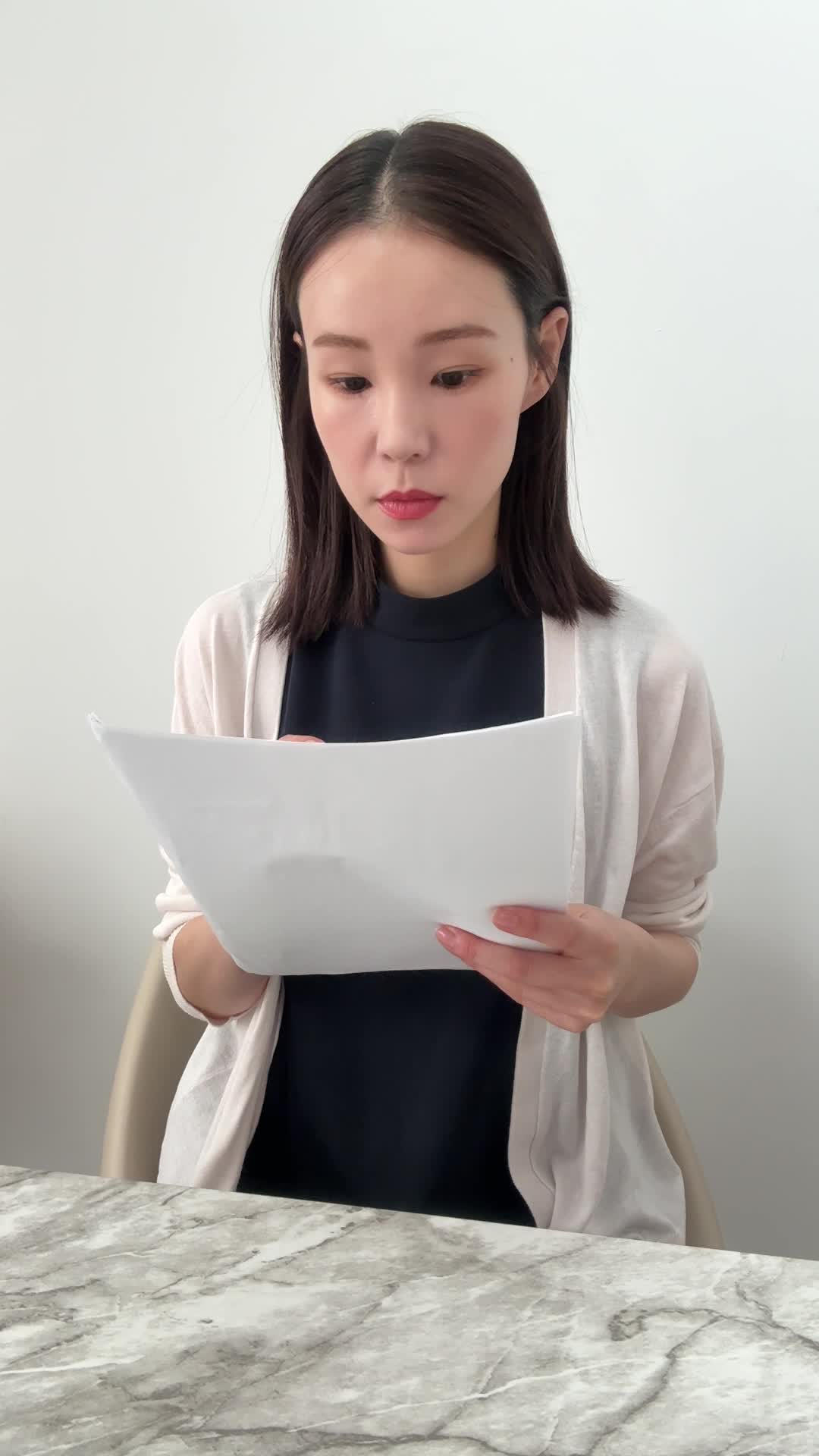 テーブルで契約書にサインをしようとして「最後の確認」をしている動作