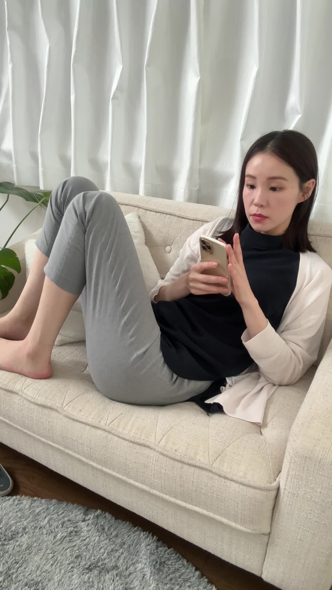 ソファーで脚を伸ばし、スマホの画面を見ながら「契約前にチェックするポイント」を確認する表情