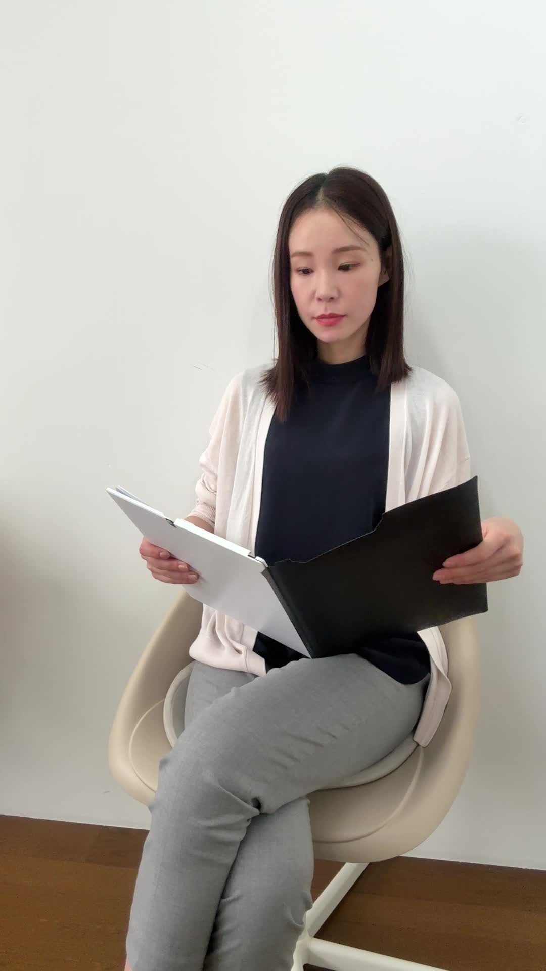 椅子に腰掛け、資料を閉じて「これで次のステップに進もう」と決意を示す表情