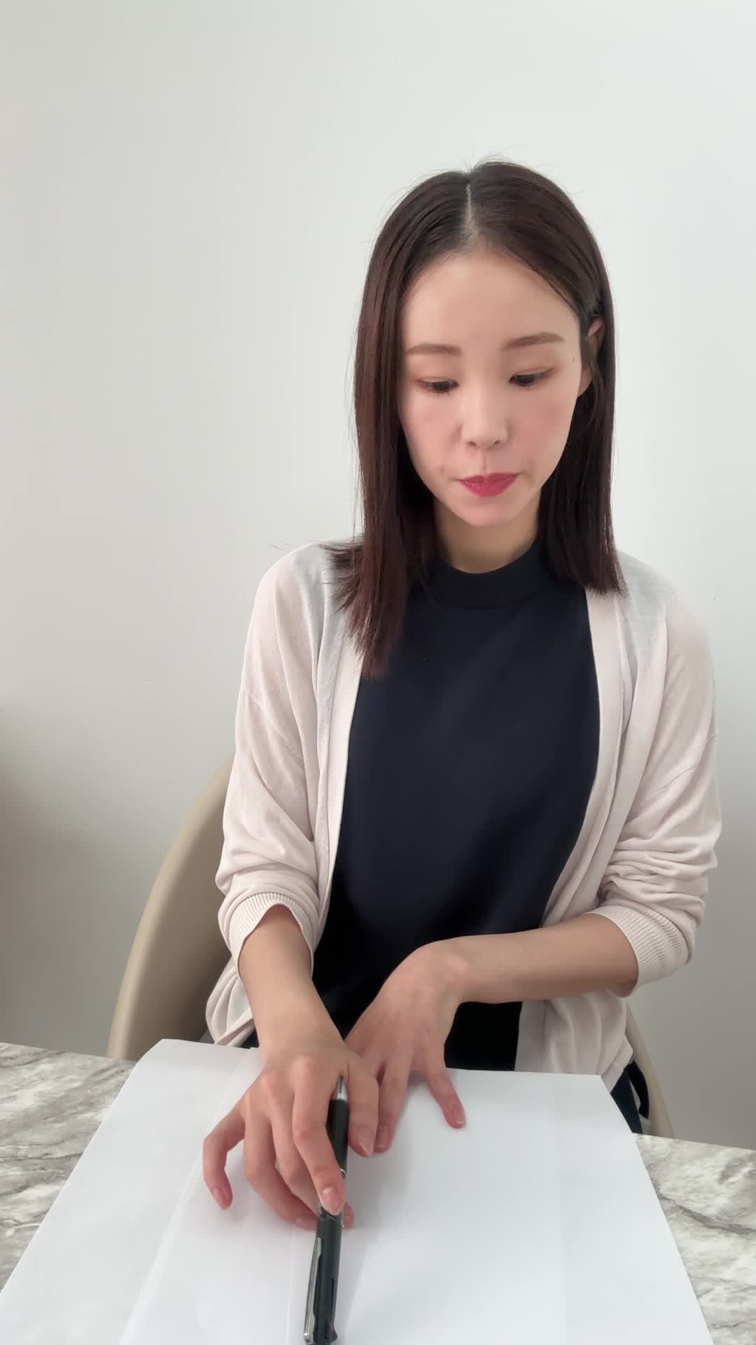 椅子に座り、テーブルに広げた資料を指でなぞりながら真剣に考え込む表情