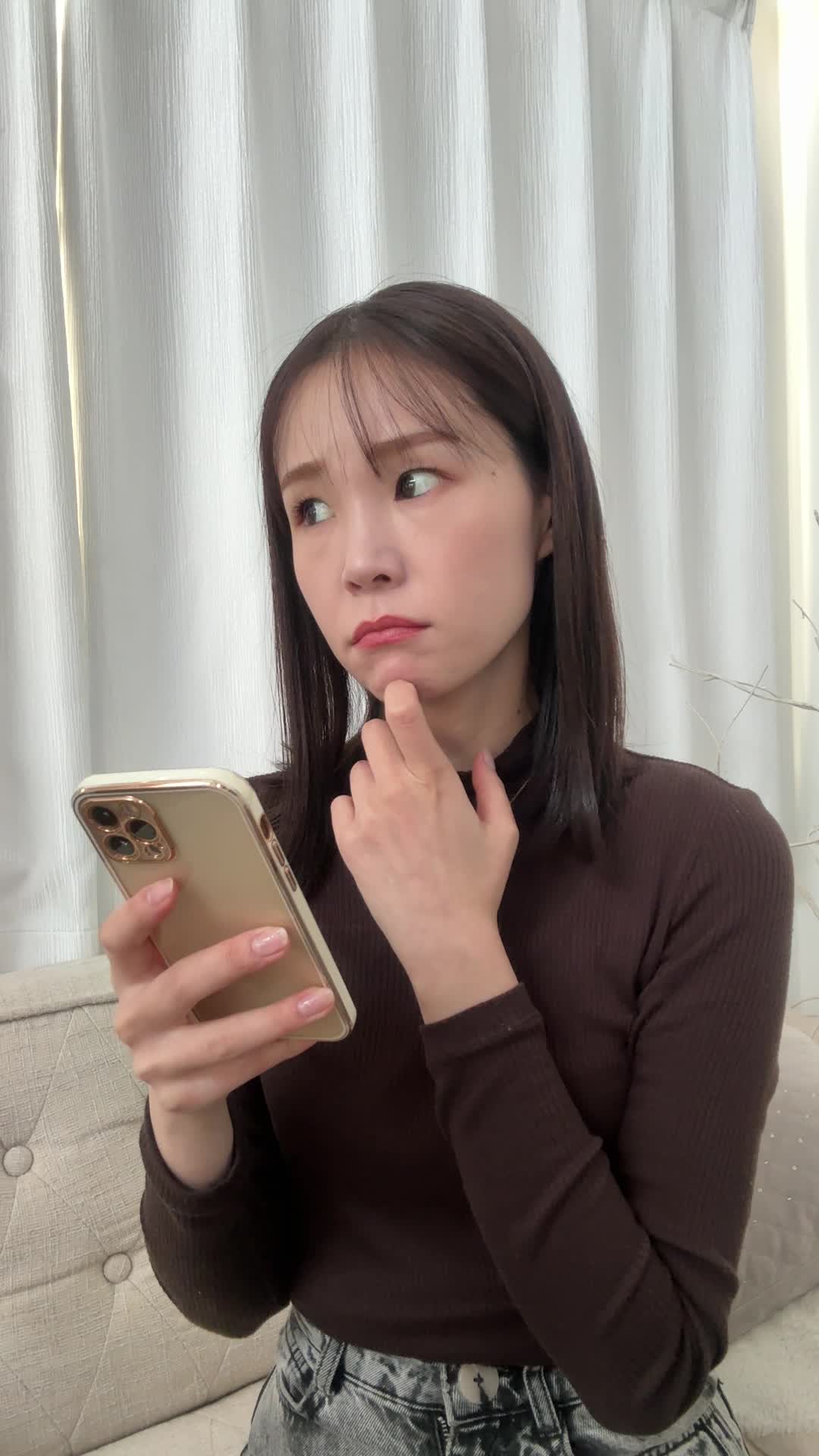 スマホを見て首をかしげ、「ちょっと怪しい？」と眉を上げる動作