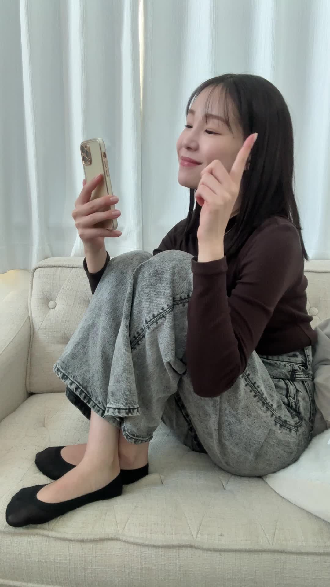 ソファでスマホを指差し、「ほら、これ！」と確信に満ちた笑顔