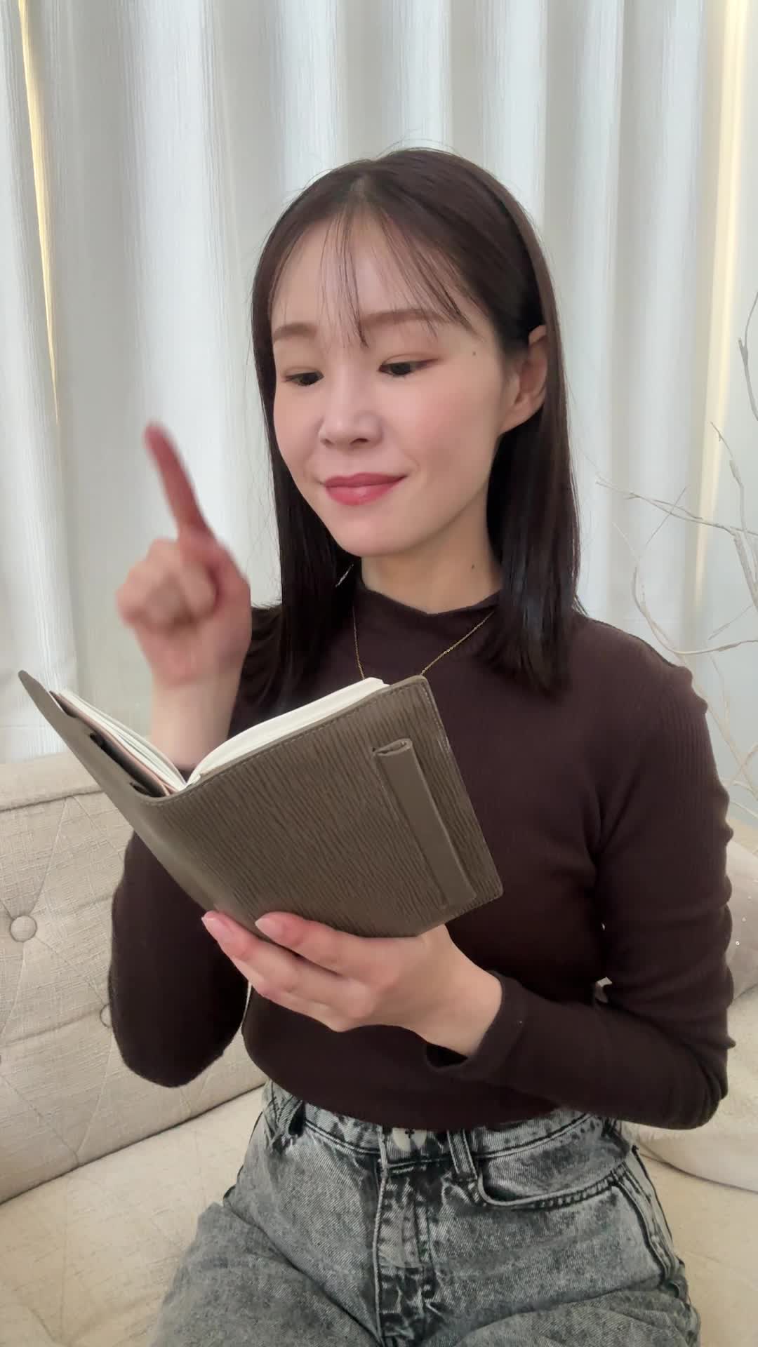 手帳を指差しながら、「これが目標だ！」という決意を表す動作