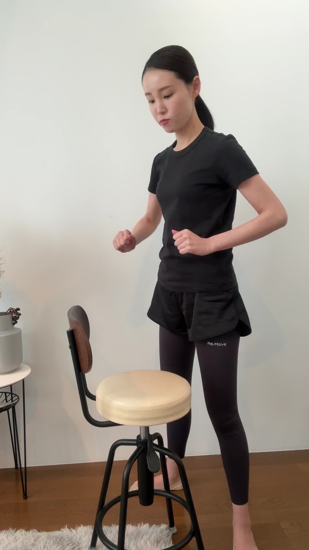 椅子を使ってスクワットをするが、途中でバランスを崩すコミカルな動作