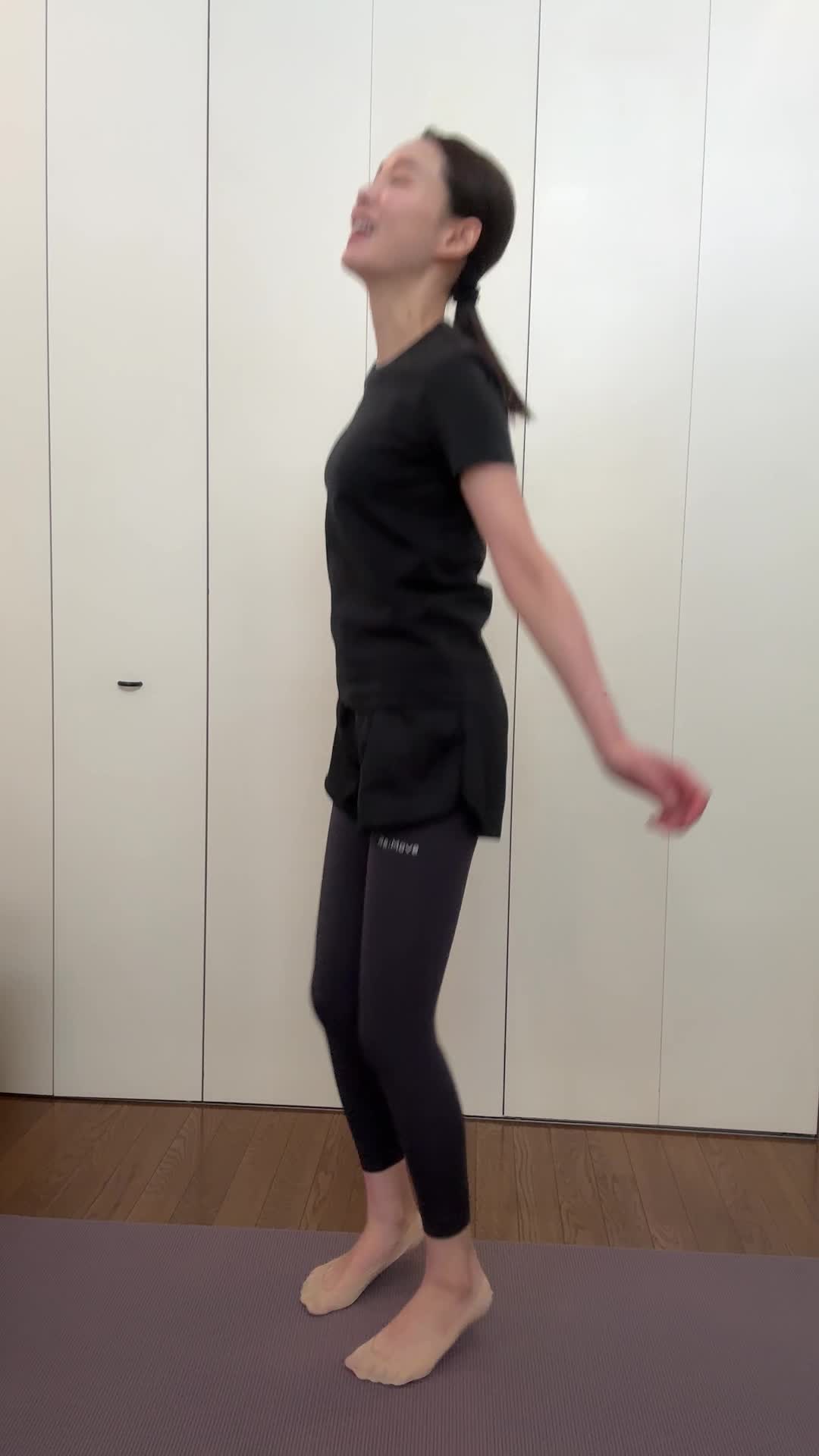 ヨガマットの上で軽くジャンプして「なんか運動っぽい！」と笑顔を見せる動作