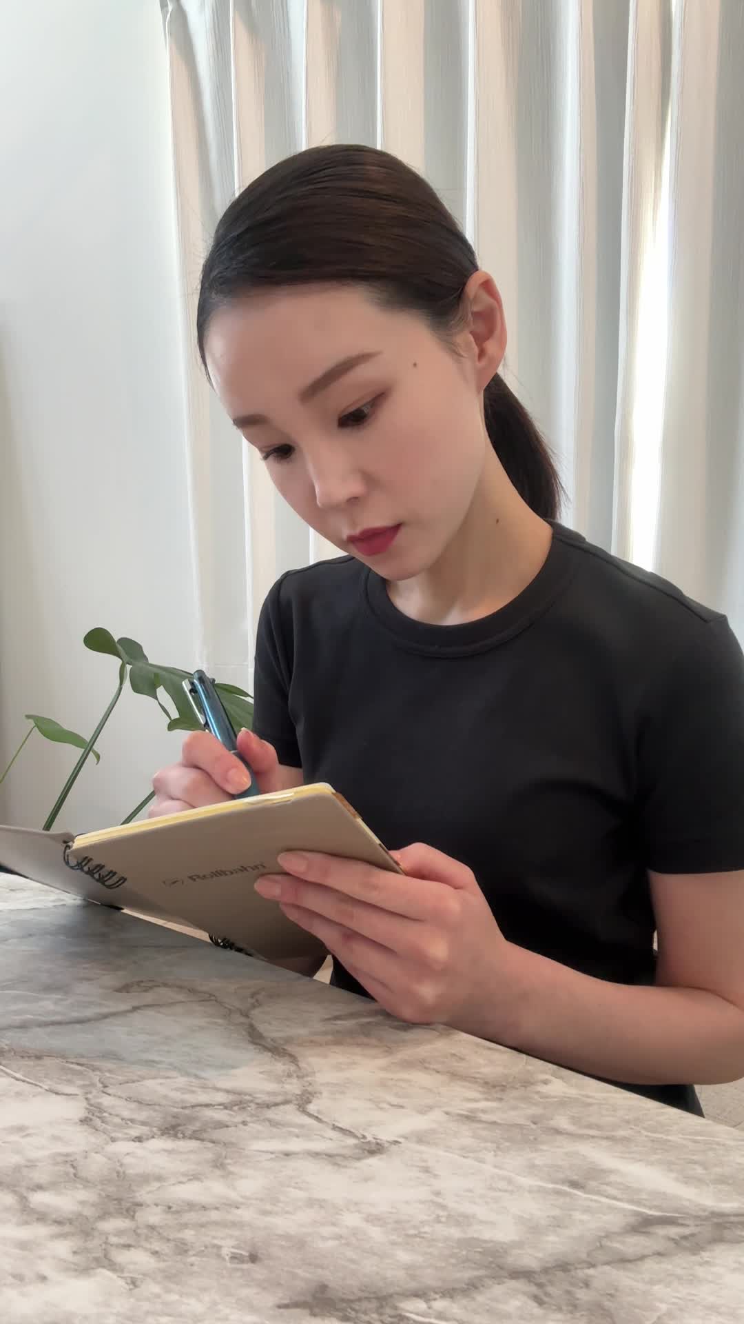 テーブルで手帳を開き、エクササイズのスケジュールを書き込みながら頷く姿