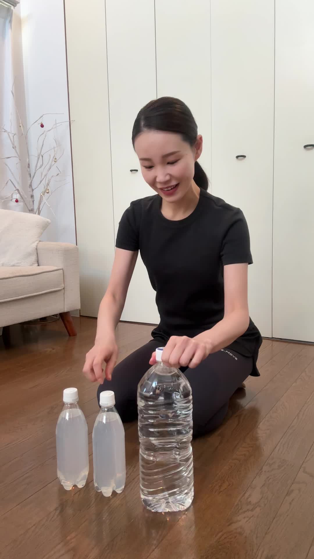 床にペットボトルを並べて、「これで筋トレグッズ完璧！」と微笑む表情
