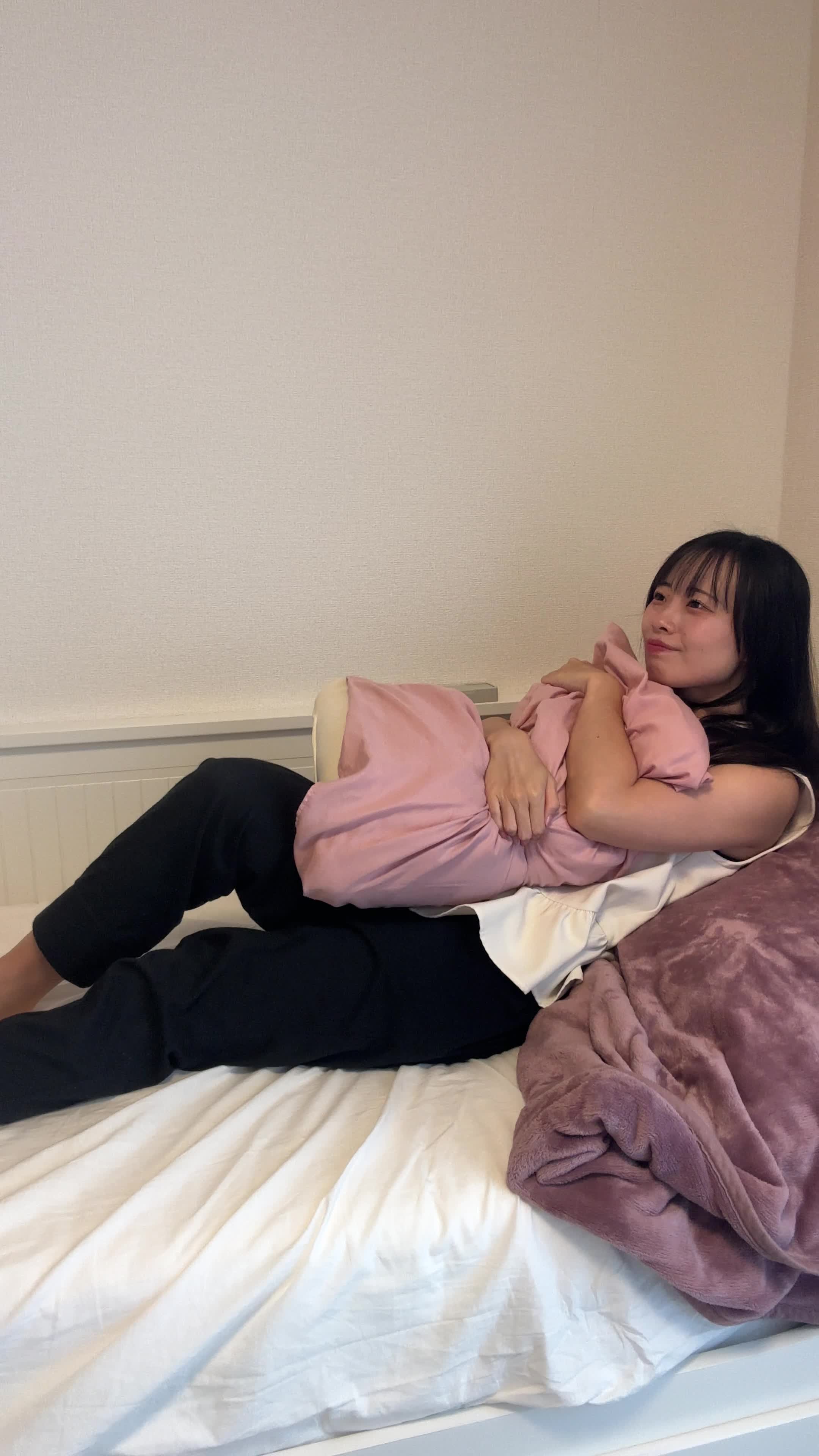 ベッドでクッションを抱きしめ、「髪がまとまったらどんな気分だろう」と期待に胸を膨らませる姿