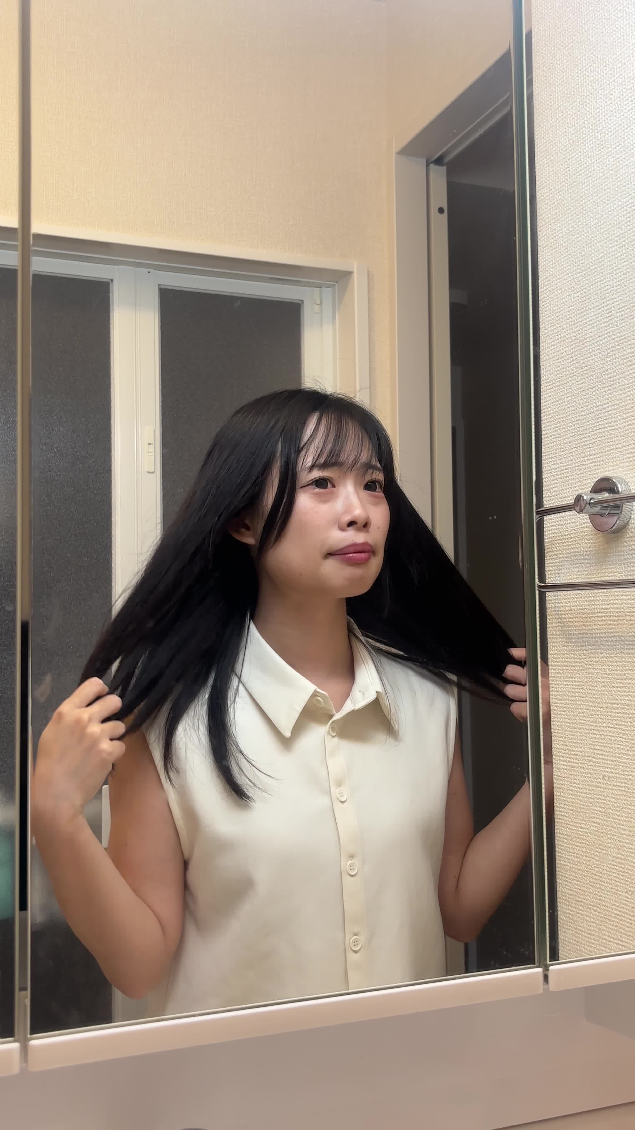 鏡の前で髪を触りながら、「この広がりをどうにかしたい」と悩む姿