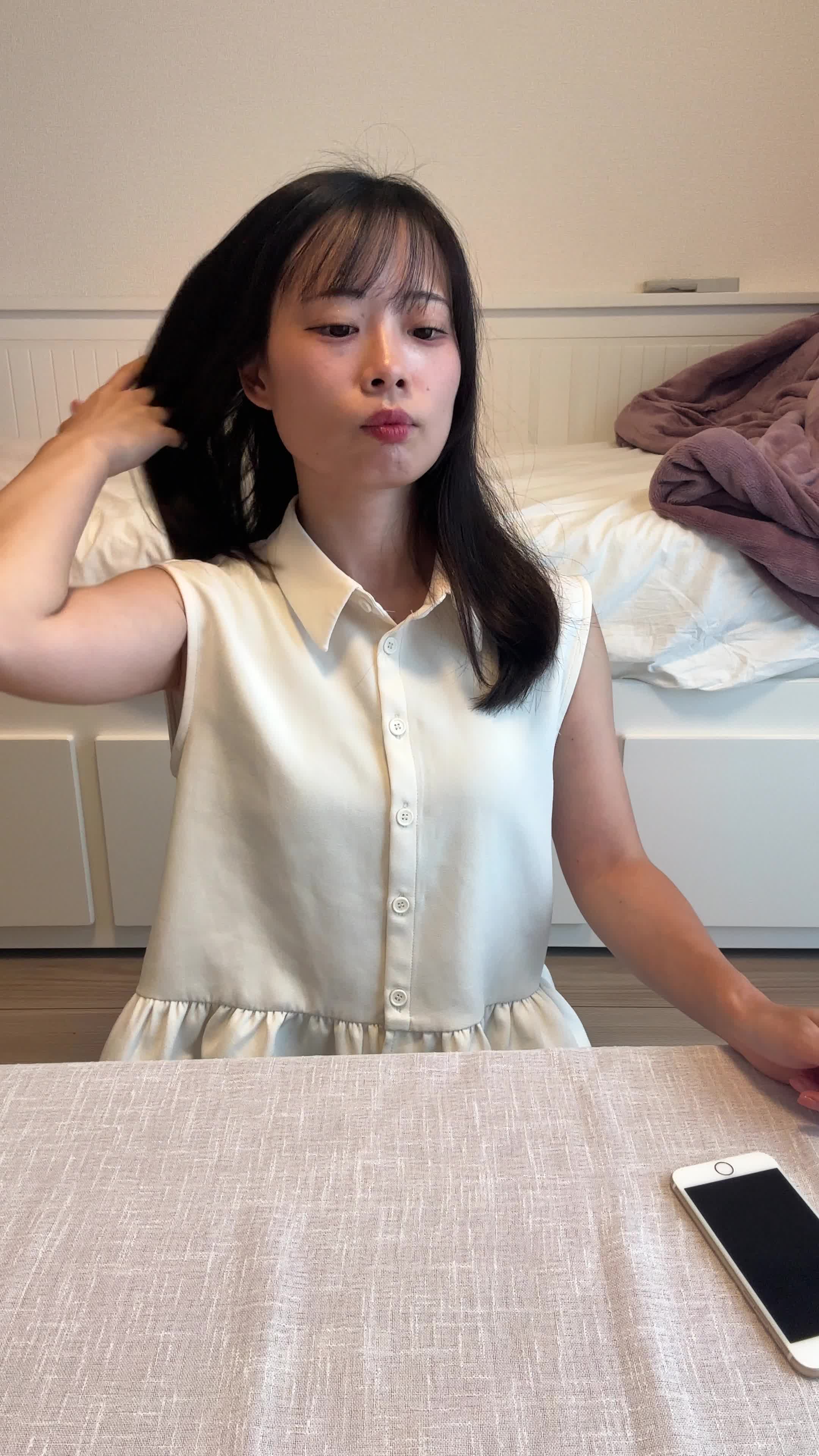 テーブルに置いたスマホの画面を見て、「サロン帰りの髪が自宅でも再現できる？」と期待する表情