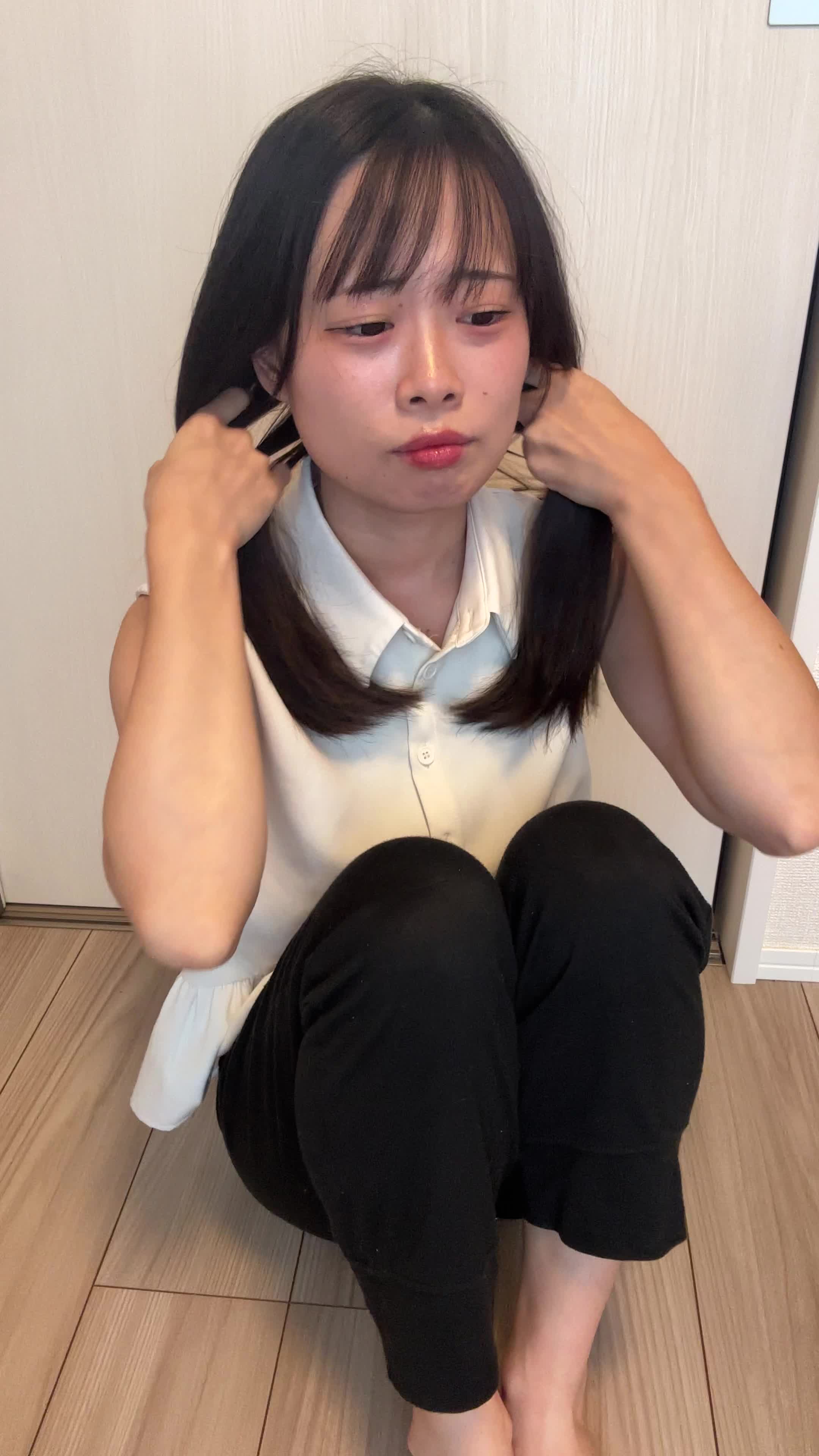 床で膝を立てて座り、「髪がまとまらなくて朝から大変」と困った様子を見せる仕草