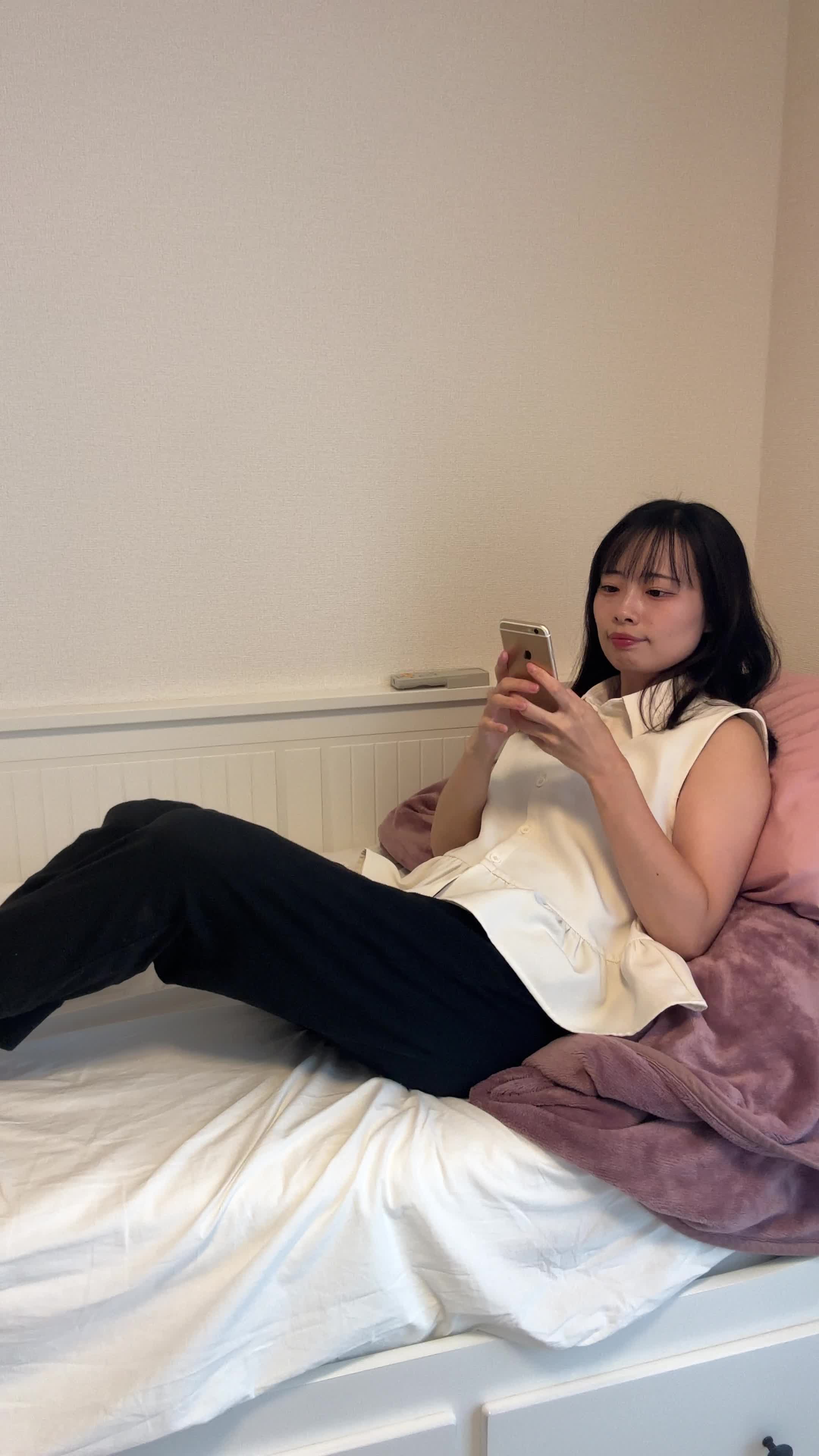 ベッドで横になり、スマホで「髪をサラサラにする方法」を検索している姿