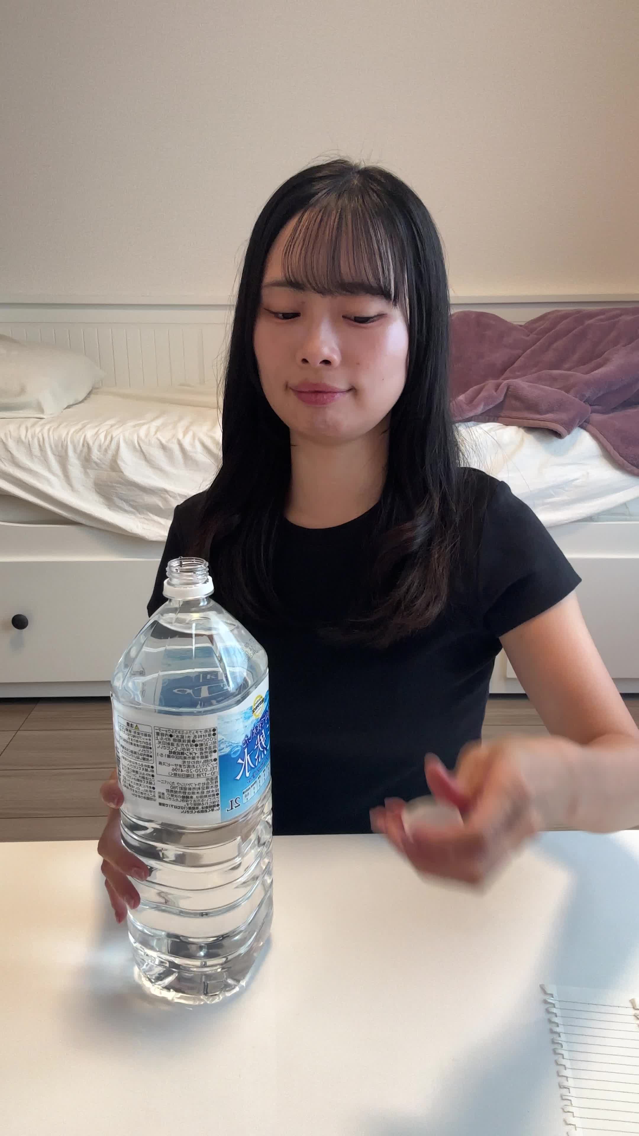 椅子に座り、ペットボトルの水を飲みながら「もっと手軽に冷たい水が飲めたらいいのに」と考える表情