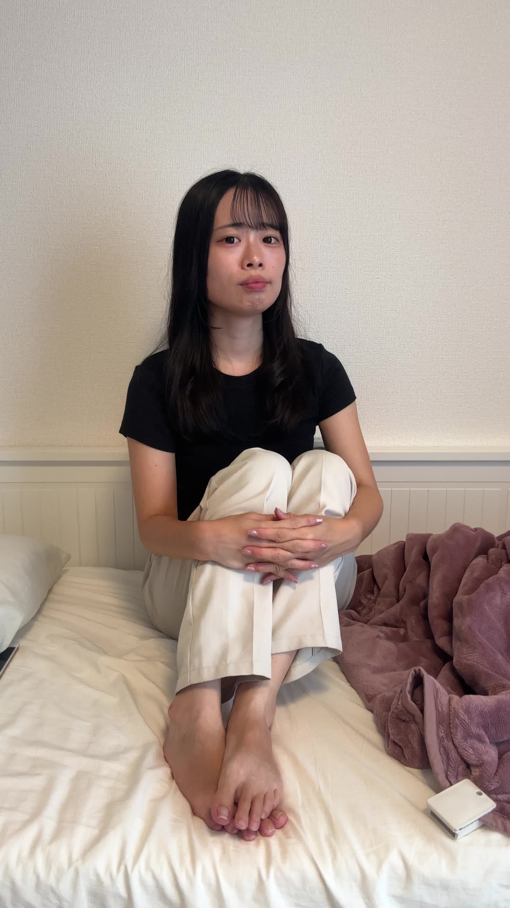 ベッドで膝を抱え、熱いお茶を飲みたいけど準備が面倒そうな顔をして悩む様子