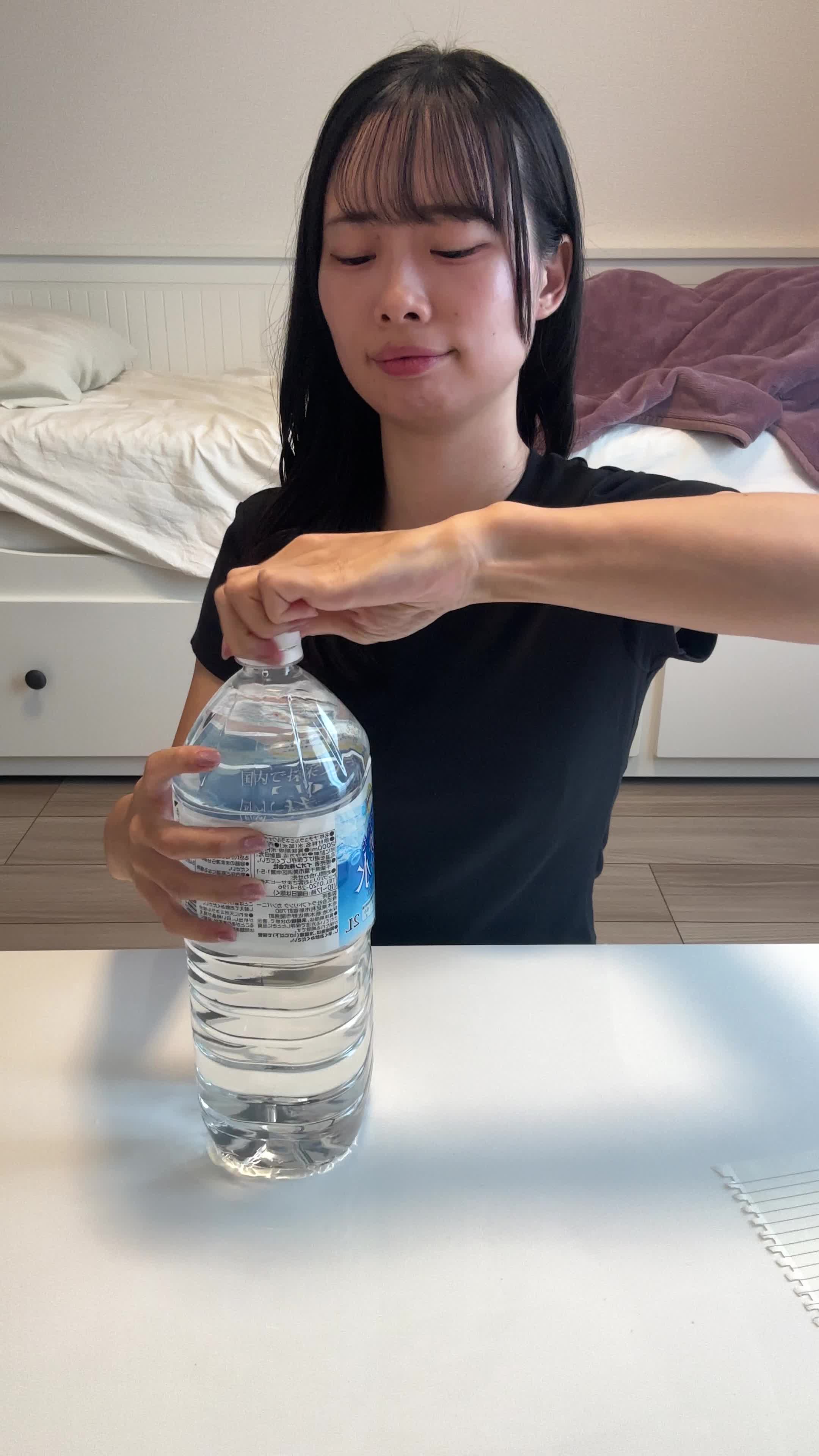 テーブルでペットボトルの蓋を開け、「もっと手軽にできる方法が欲しい」と悩む表情