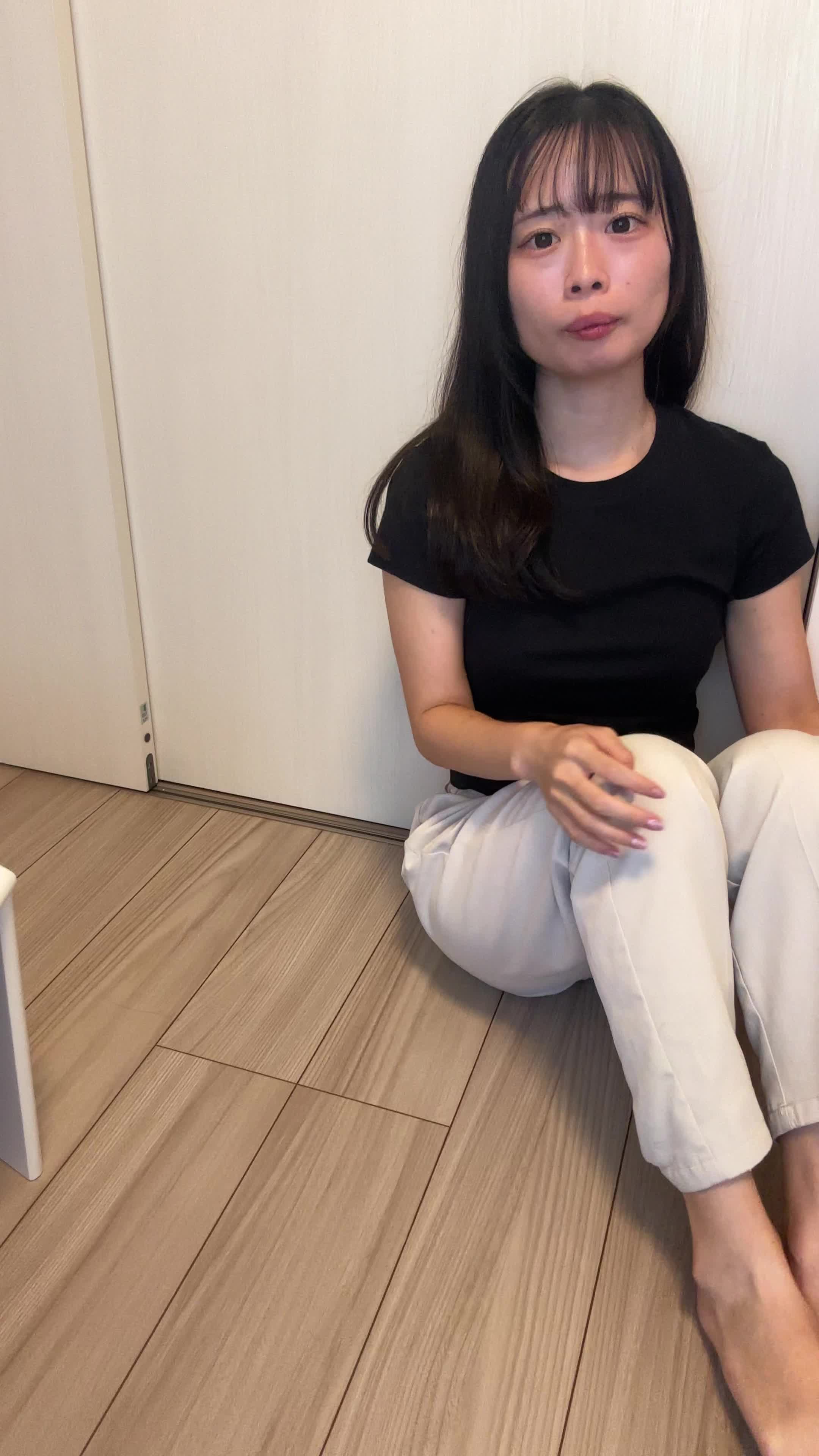 床に座り込み、スーパーの水のボトルを並べて「これを買い続けるのは大変」とため息をつく表情