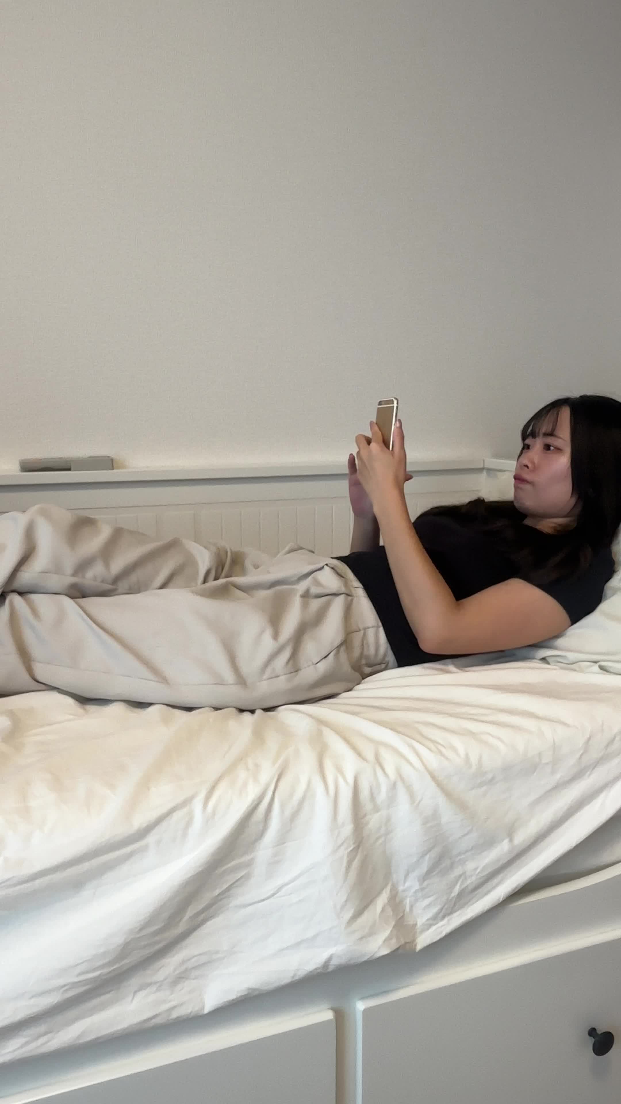 ベッドで脚を伸ばし、「冷たい水がすぐに飲めたら…」とスマホで調べる姿