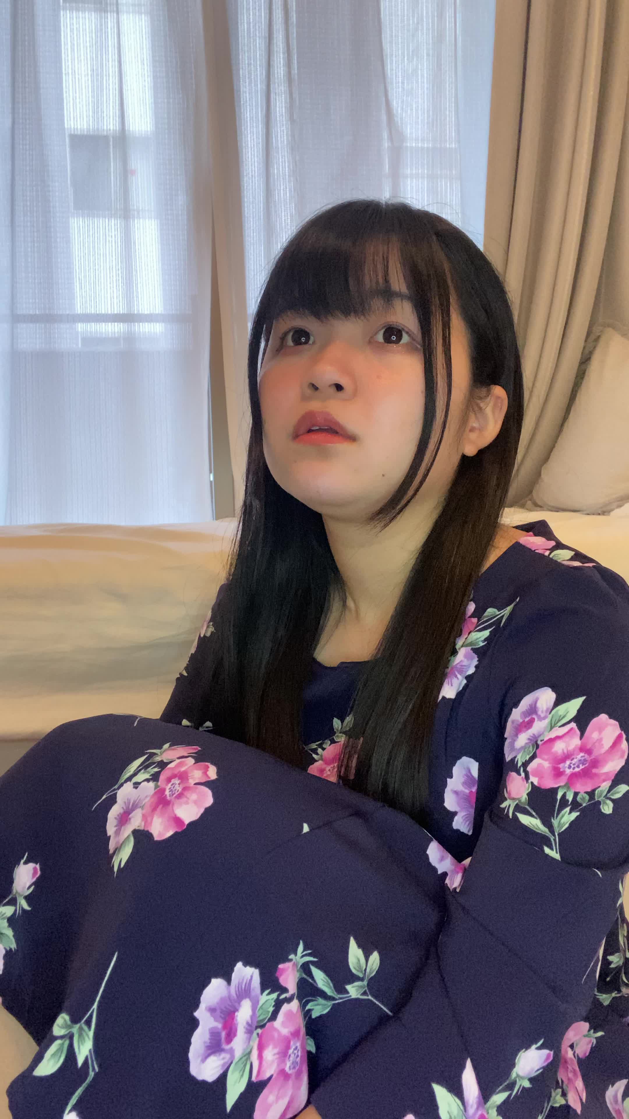 床で膝を抱え、「笑顔にもっと自信が持てるようになりたい」と考え込む様子