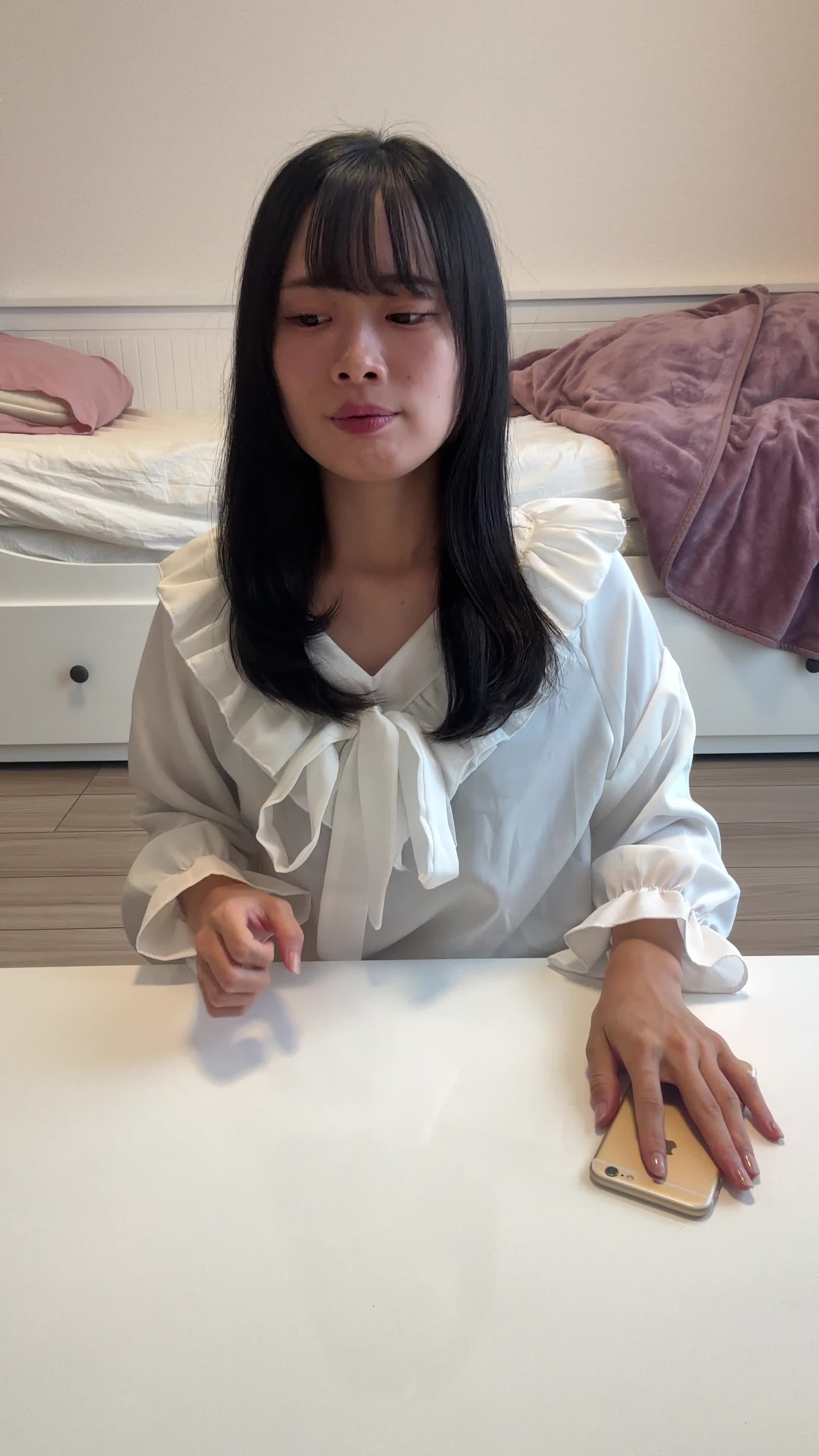 椅子に腰掛け、スマホを置いて「早く観たい！」と小さくガッツポーズをする仕草