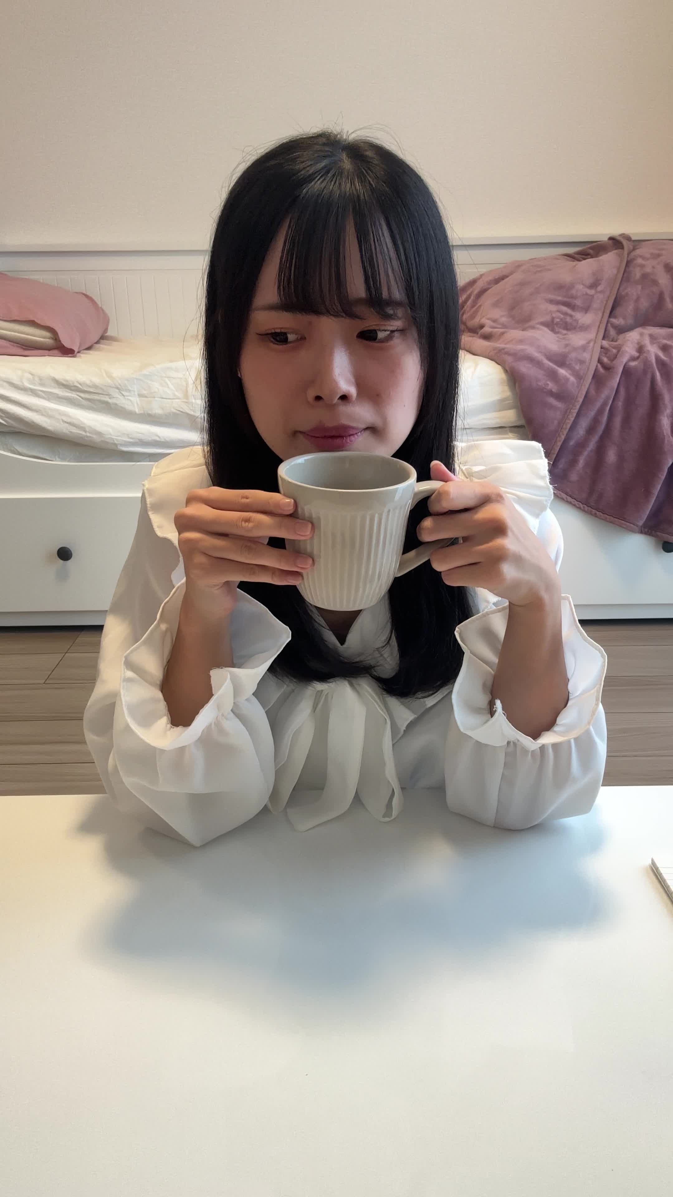 テーブルでコップを手に、「観たい作品が多すぎて迷う」と真剣に考える動作