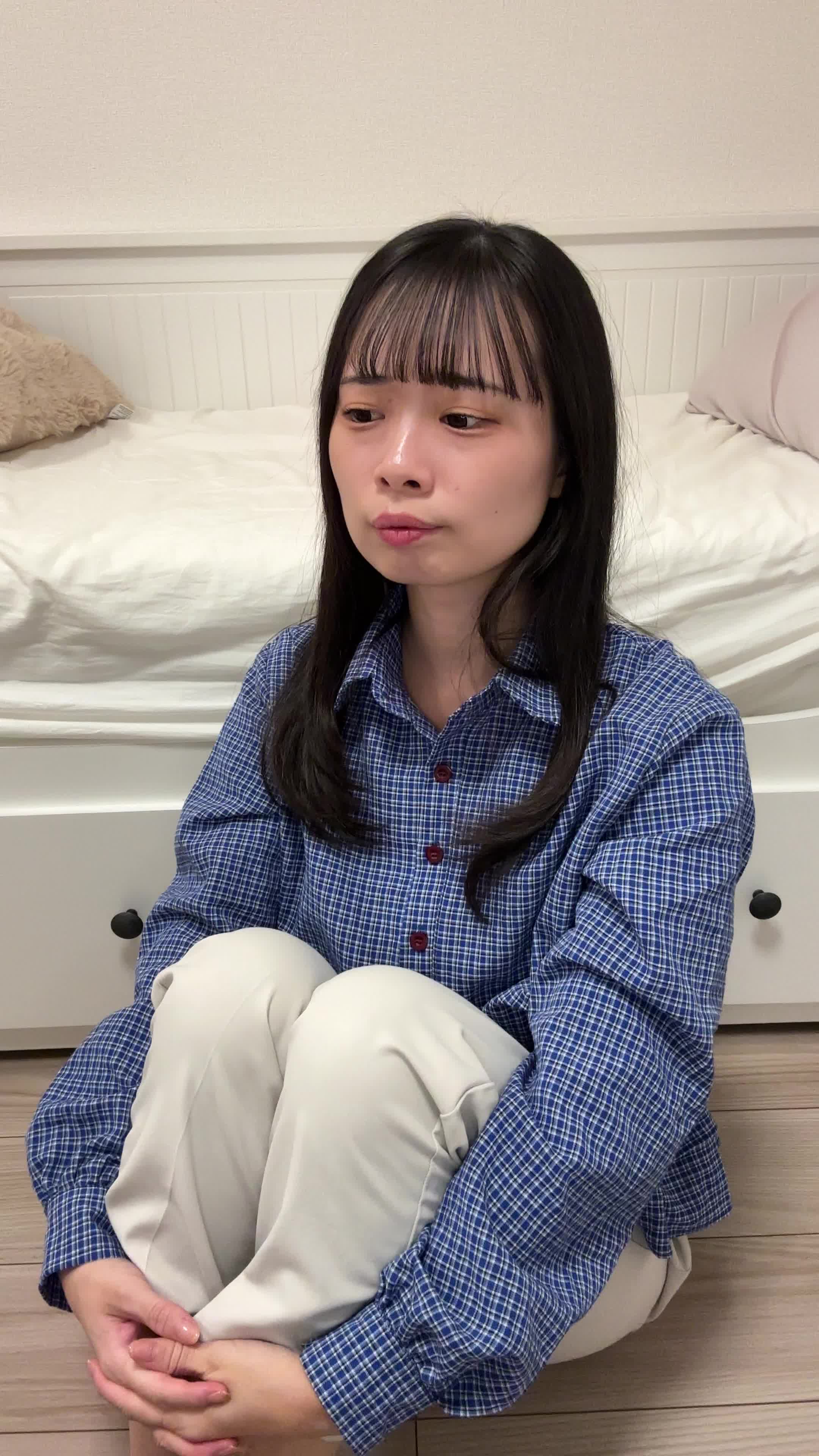 床で膝を抱え、「笑顔にもっと自信が持てるようになりたい」と考え込む様子