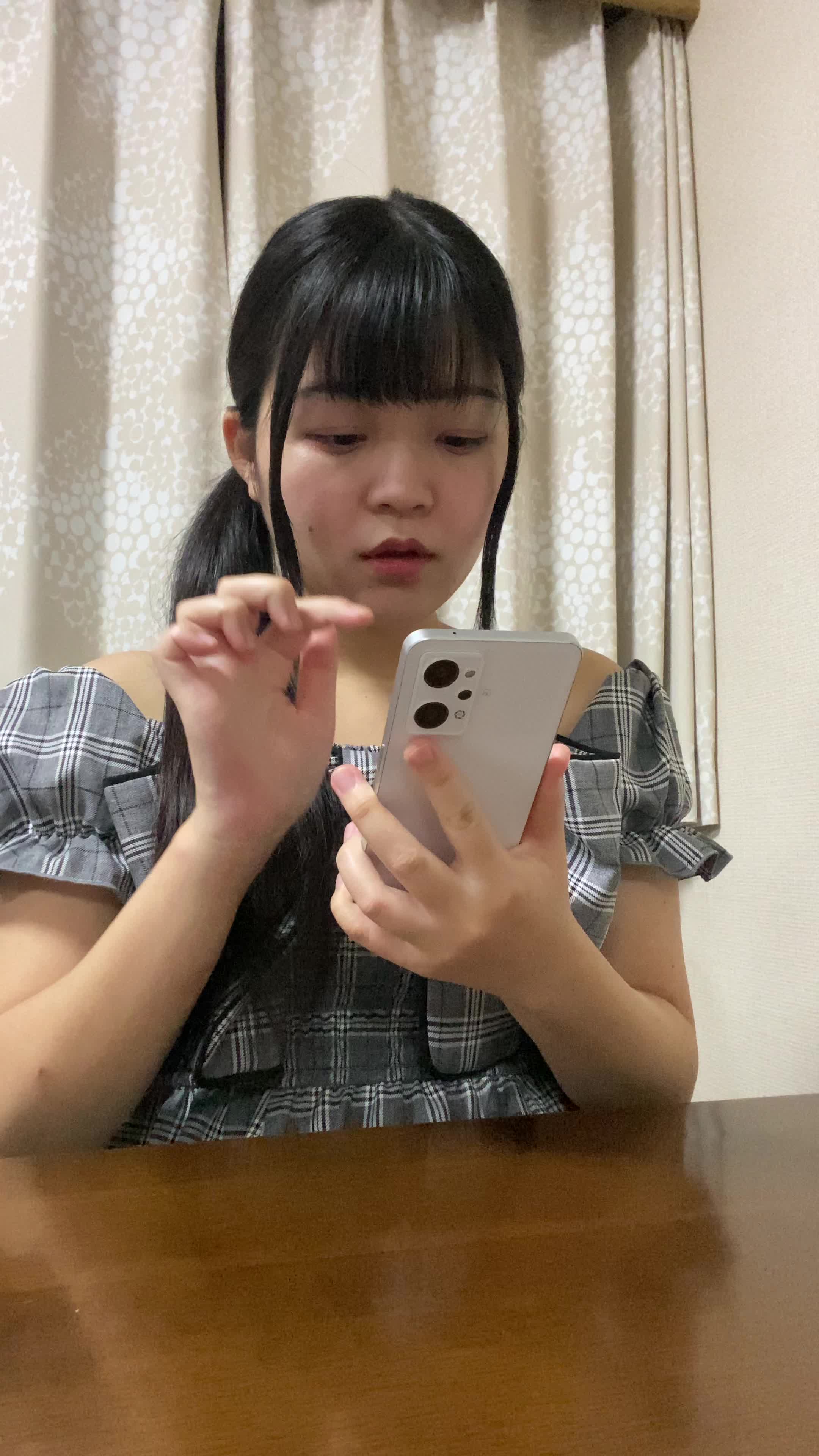 椅子に座り、スマホでカートの中身を確認しながら「これ全部買おうかな？」と悩む表情