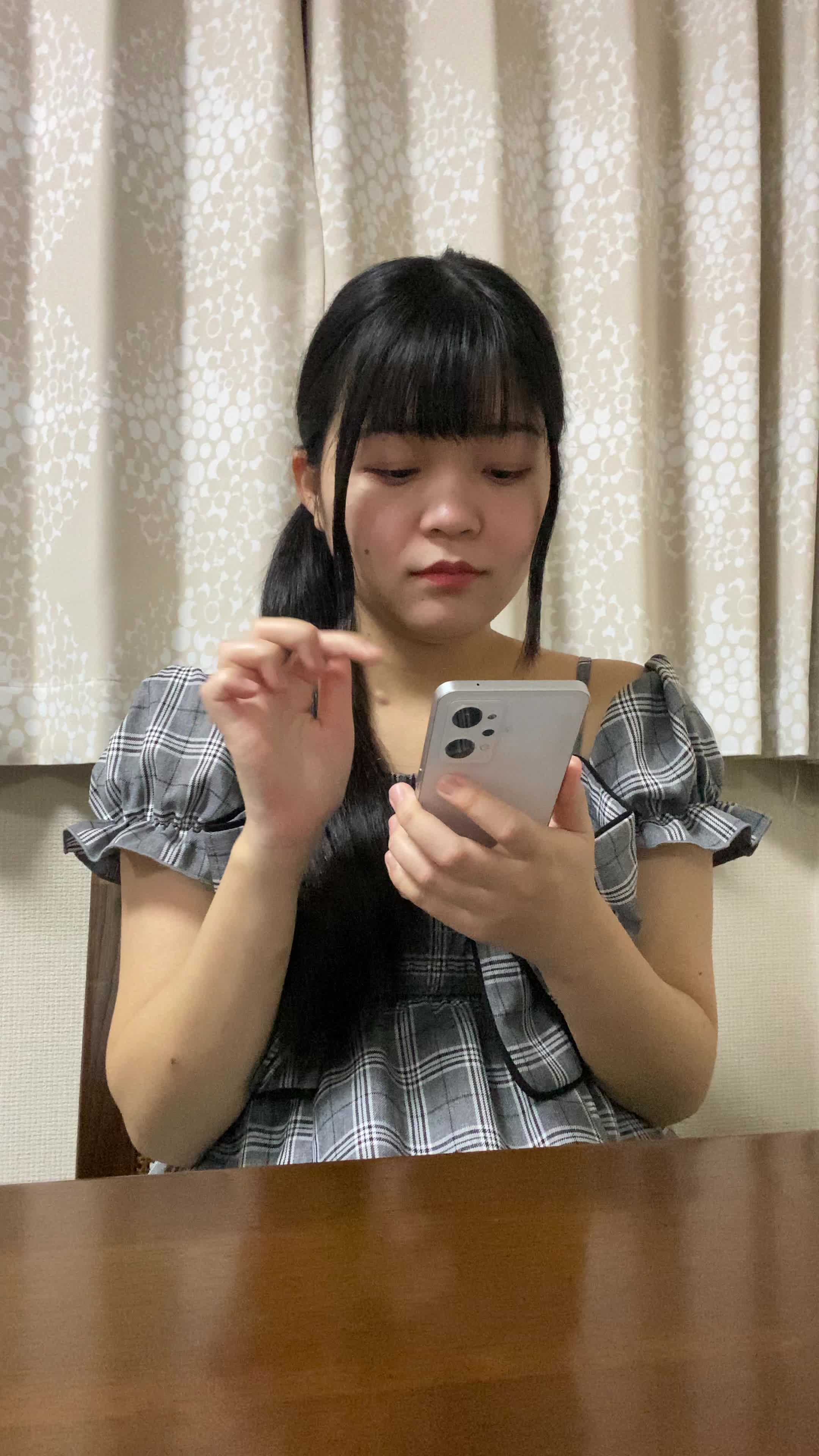 テーブルでスマホを操作し、「注文履歴を見て再注文を考える」真剣な表情