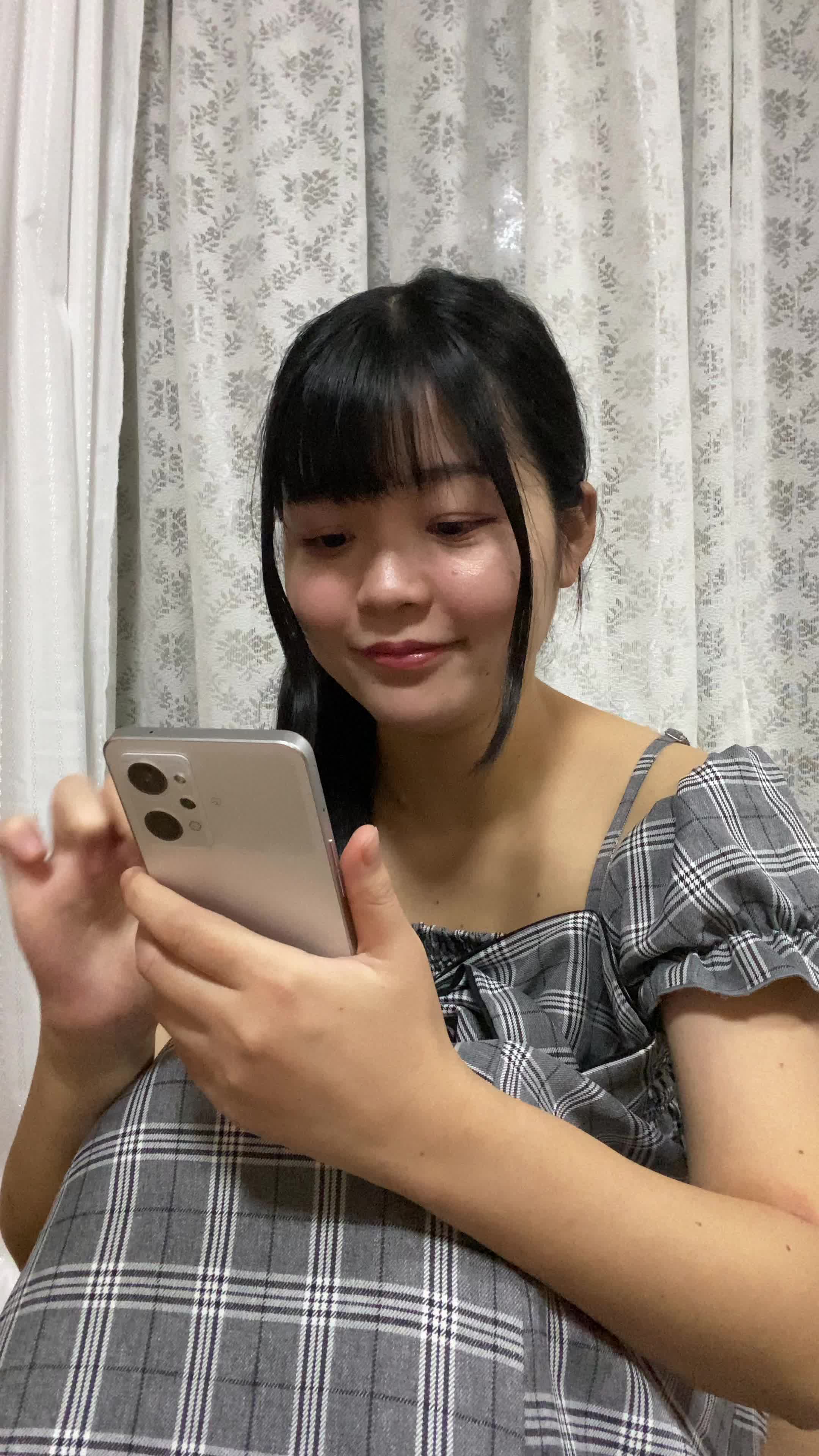 床に座り込み、スマホで商品画像を見て「このデザイン素敵！」と微笑む仕草