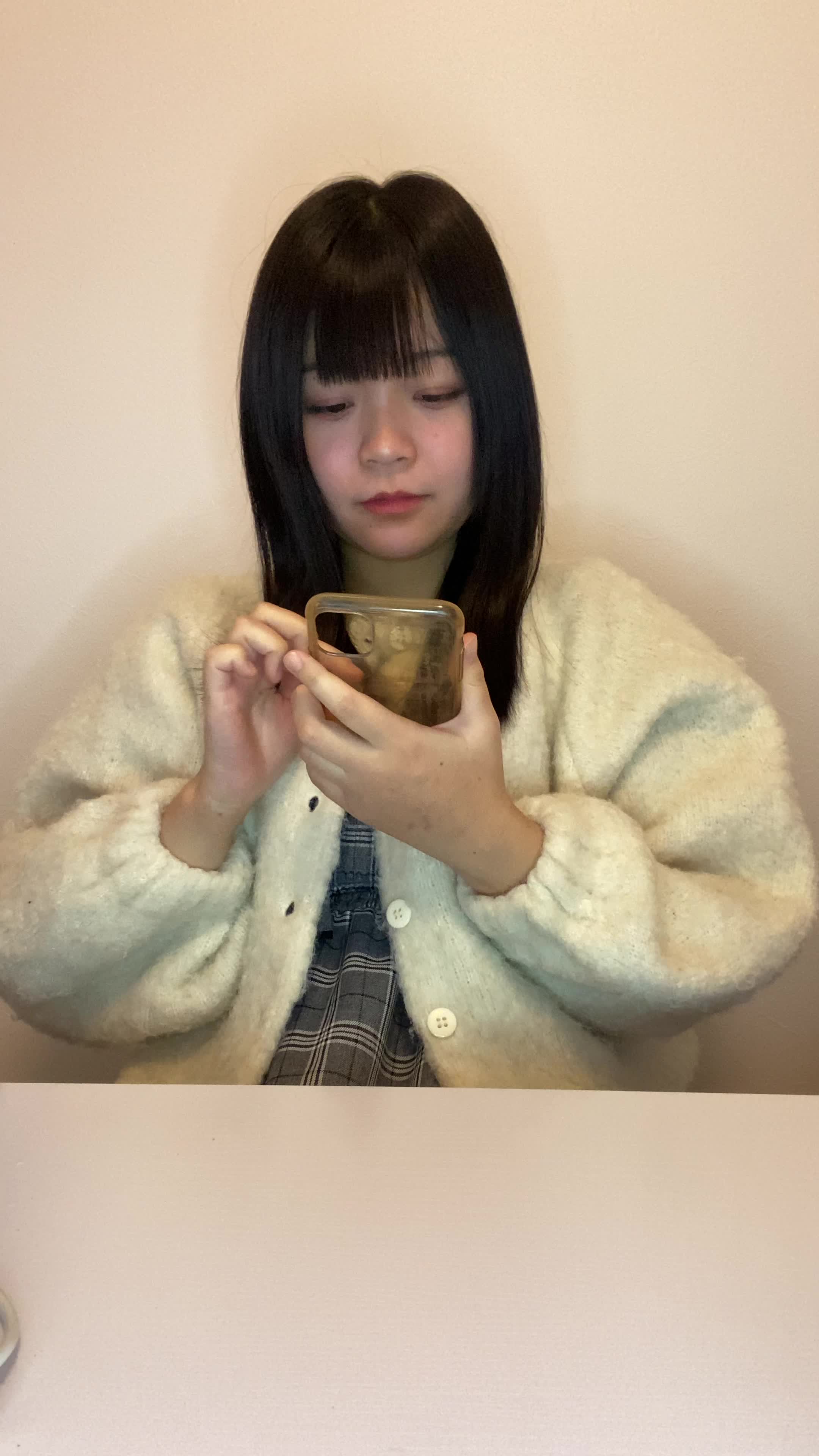 椅子に腰掛け、スマホの画面を見ながら「体臭ケアの口コミを読んで安心する」表情