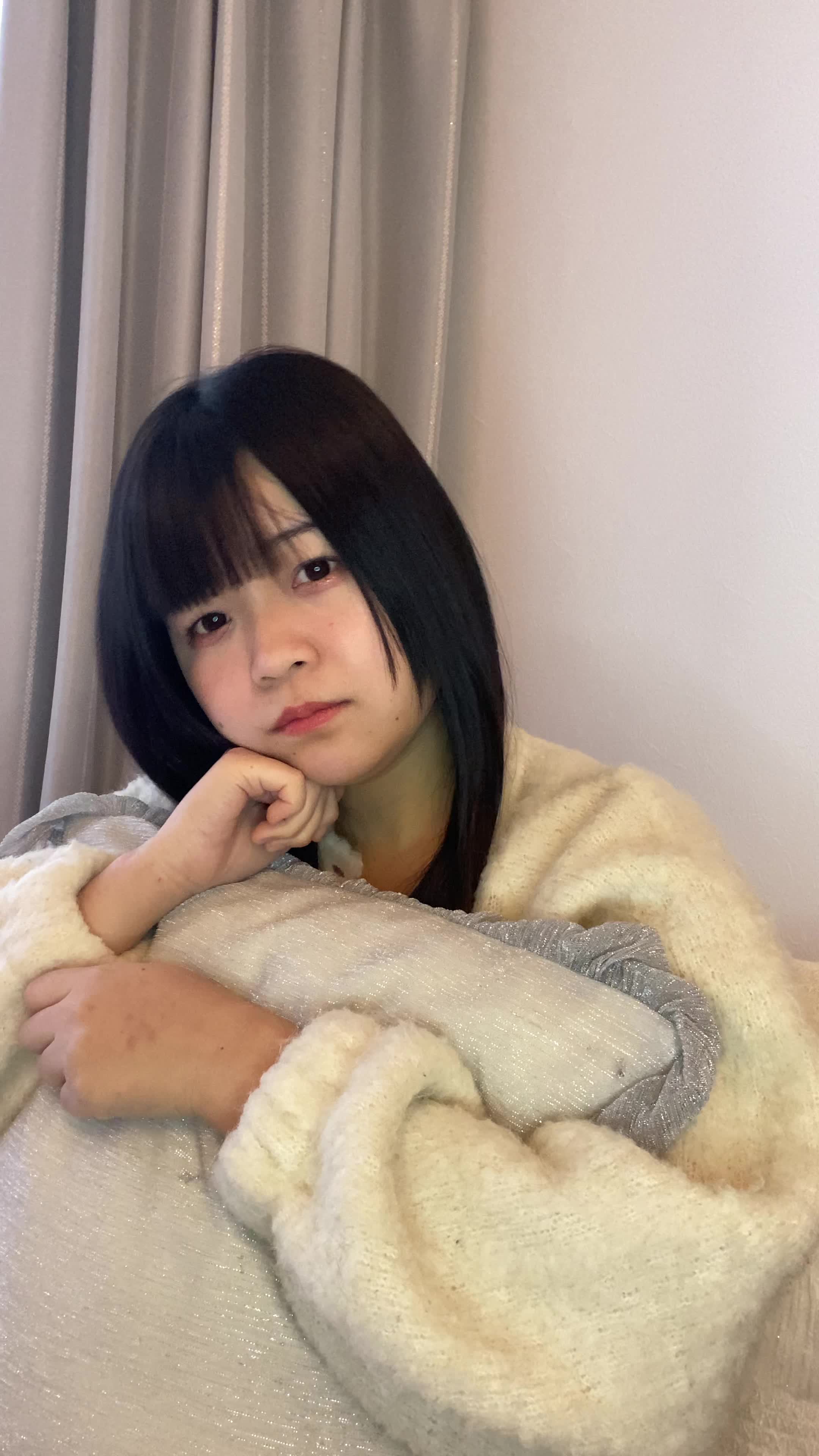 ソファでクッションを抱え、「これで匂いが改善するかな？」と悩む真剣な表情