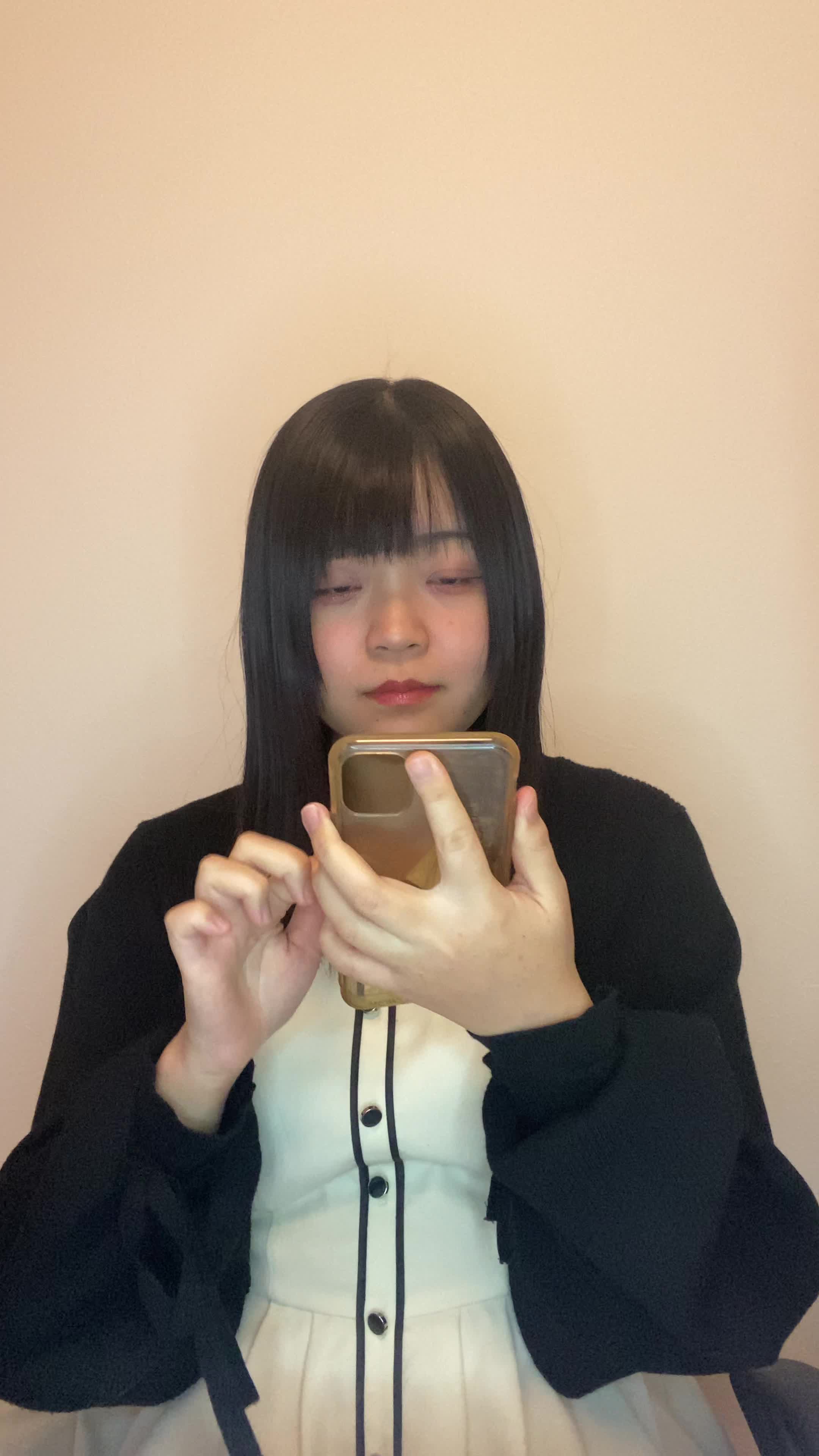 椅子に腰掛け、スマホの画面を見て「白髪ケアの口コミを読んで納得する」表情
