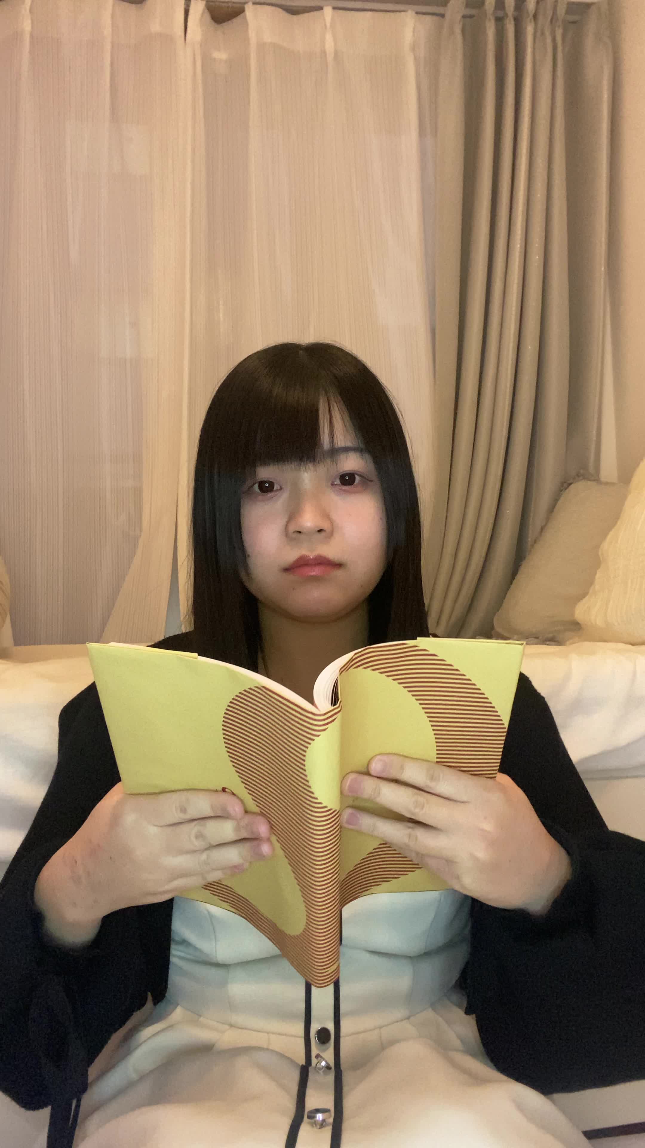 床でカタログを眺め、「白髪ケアの商品をじっくり選んでいる」様子