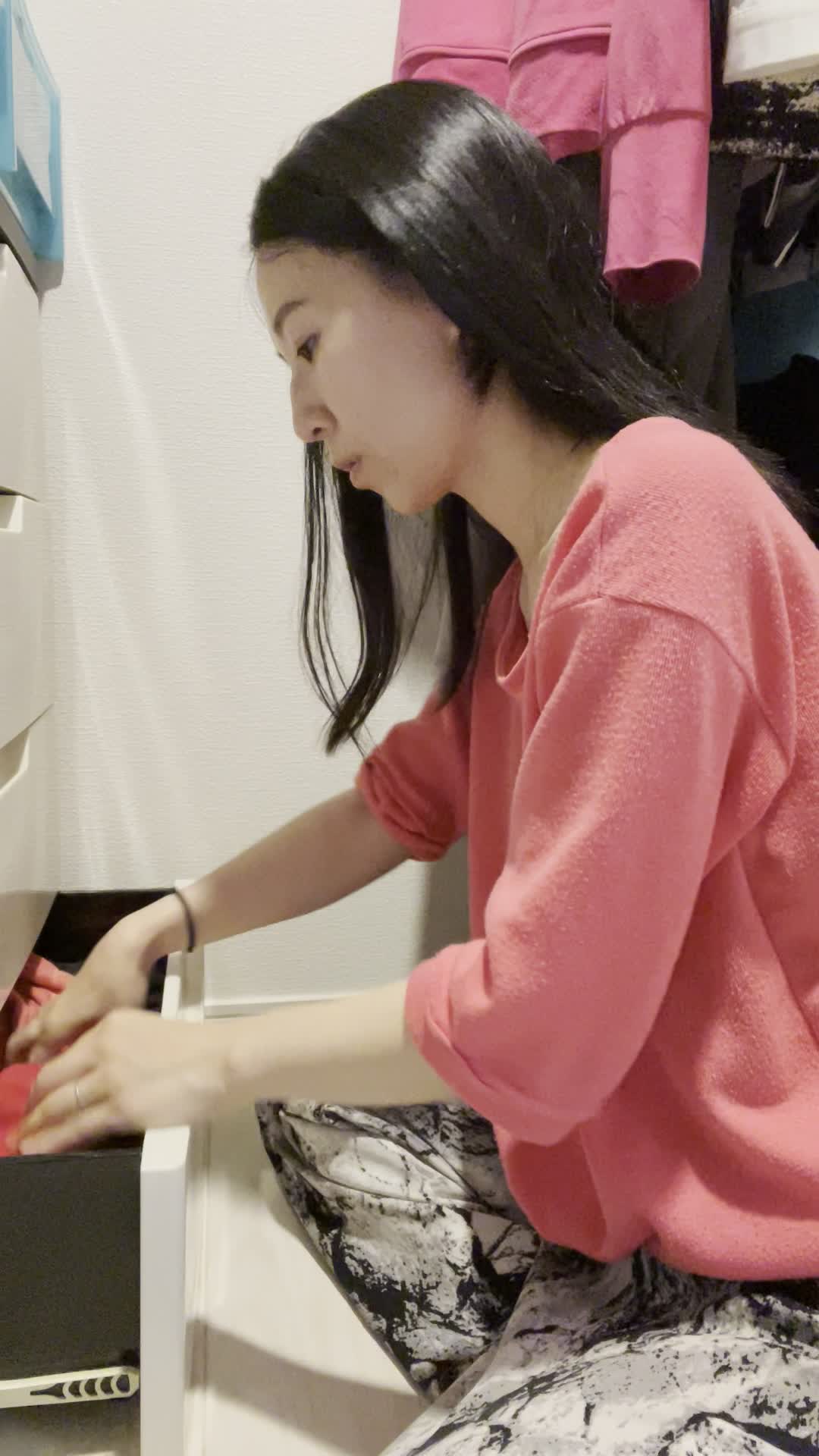 床に座り、クローゼットを開けてデート用の服を選びながら悩む仕草