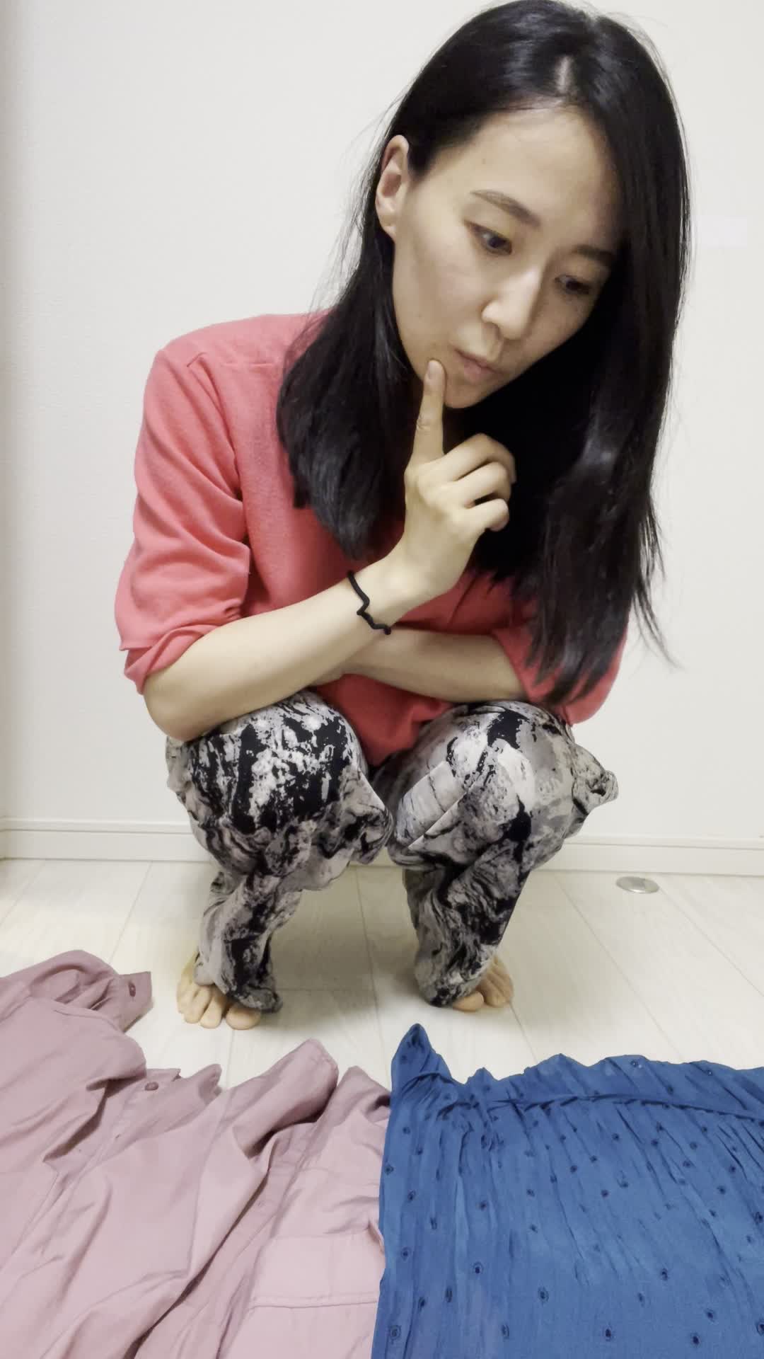 床に広げた服を一つずつ見比べ、「これが一番良さそう」と選ぶ決断の表情