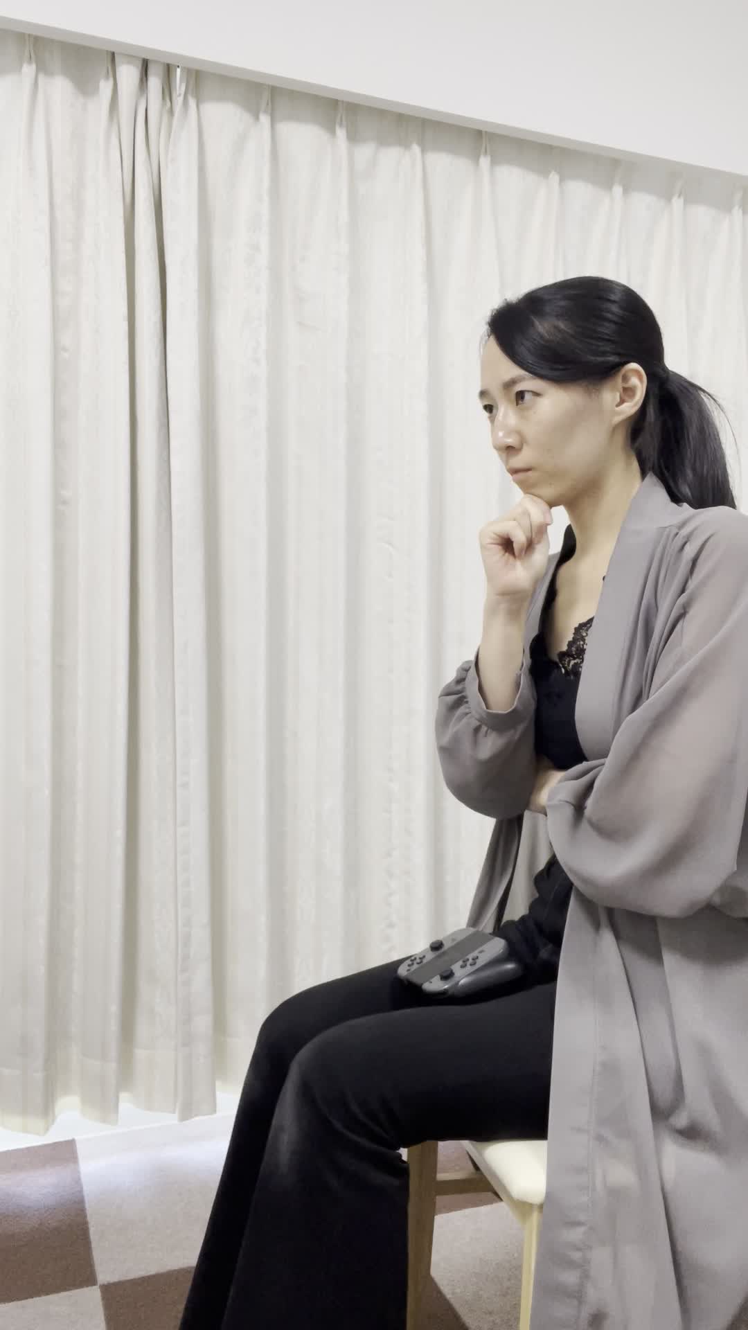 椅子に座り直し、コントローラーを置いて「次の戦略を考える」集中した表情