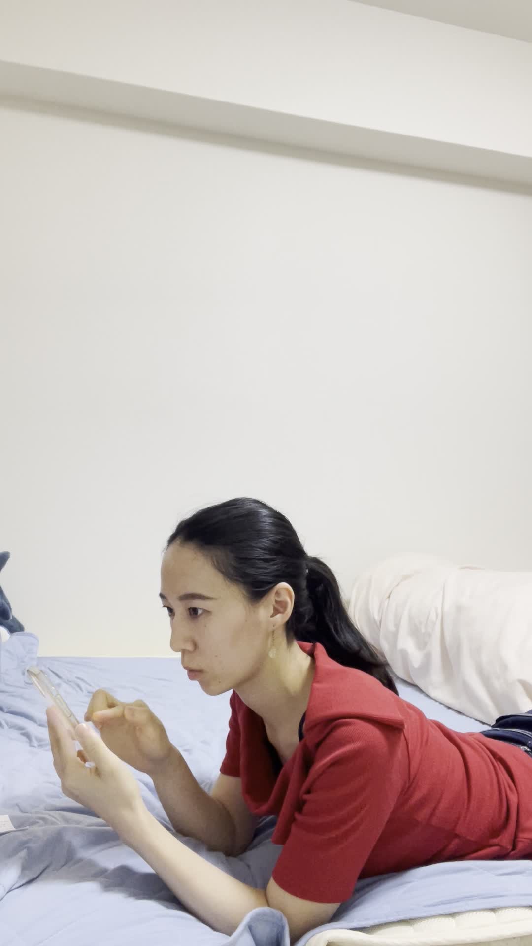 ベッドに横になり、「次に解く問題はどれだろう」とスマホを操作する動作