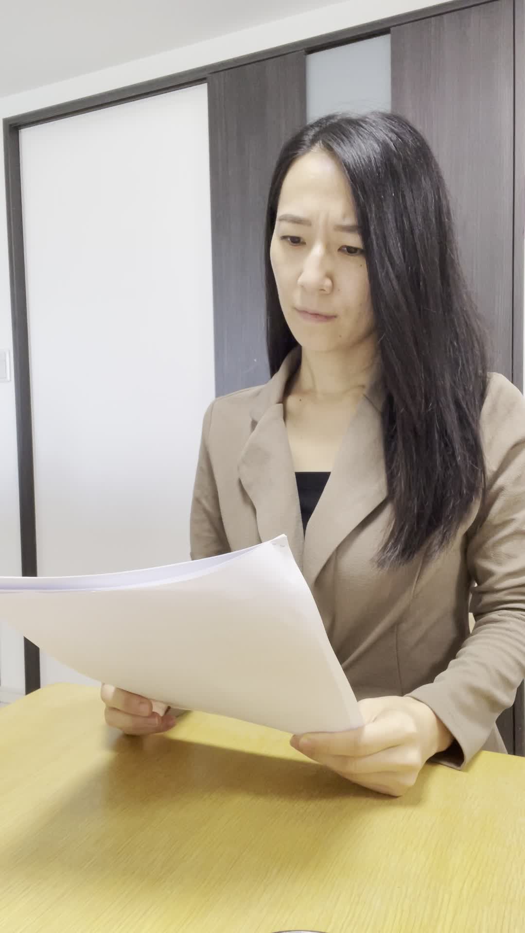 椅子に座り、テーブルに書類を広げて「どうしよう」と悩む真剣な表情