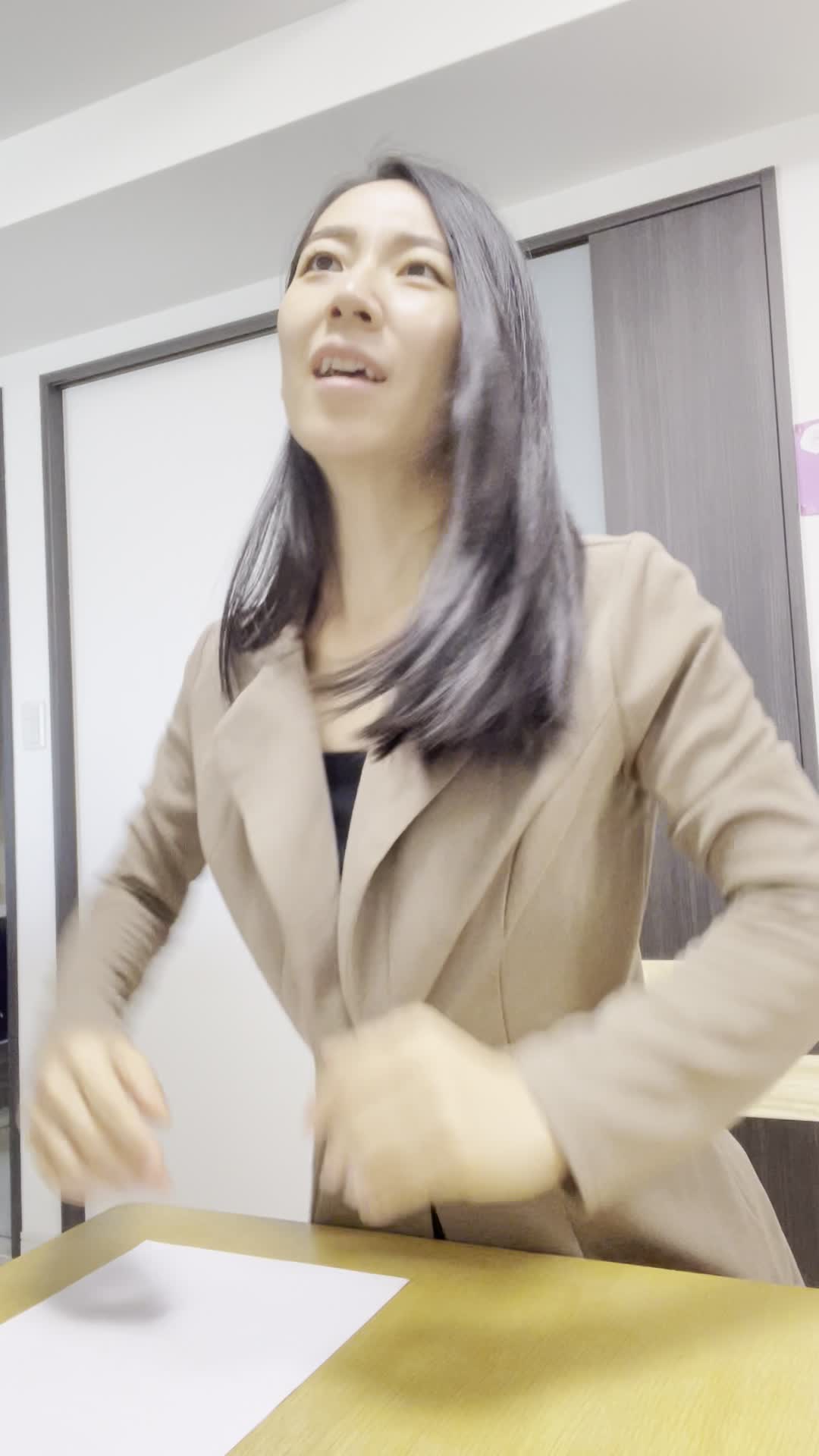 椅子から立ち上がり、「返済計画が見えた」と明るい表情を見せる動作