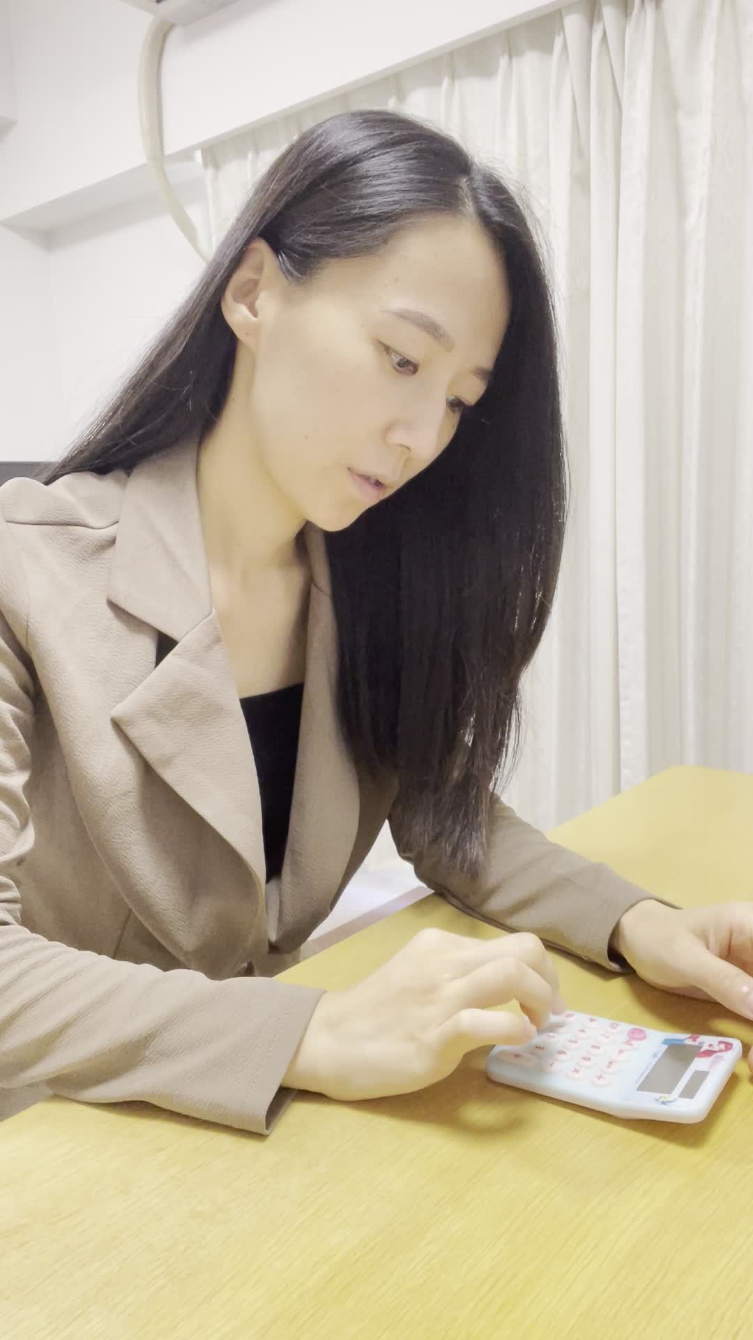 テーブルで電卓を叩き、「返済が間に合わない…」と絶望しながら頭を抱える動作